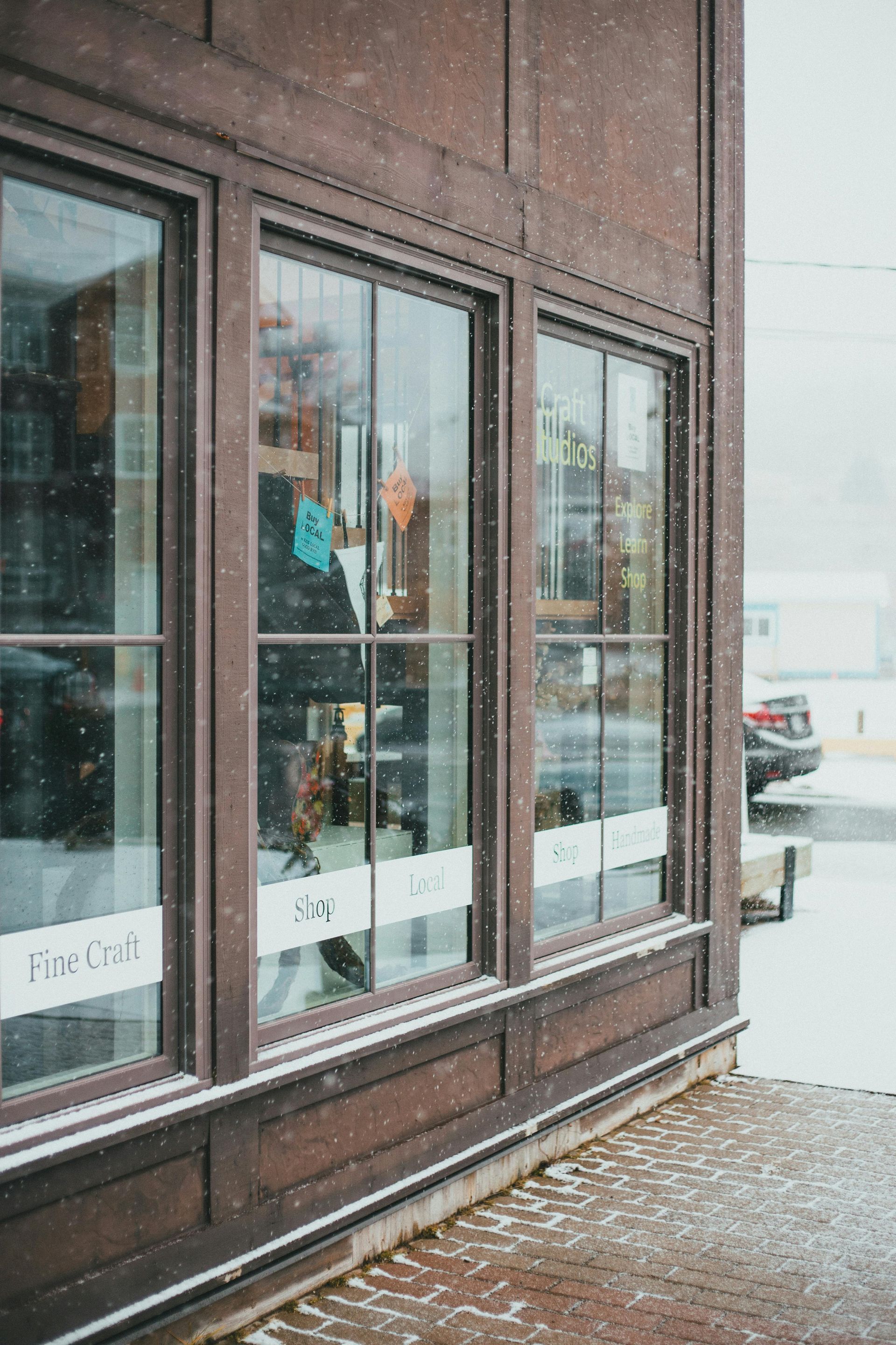 Snowy storefront with large windows and a sidewalk covered in light snow