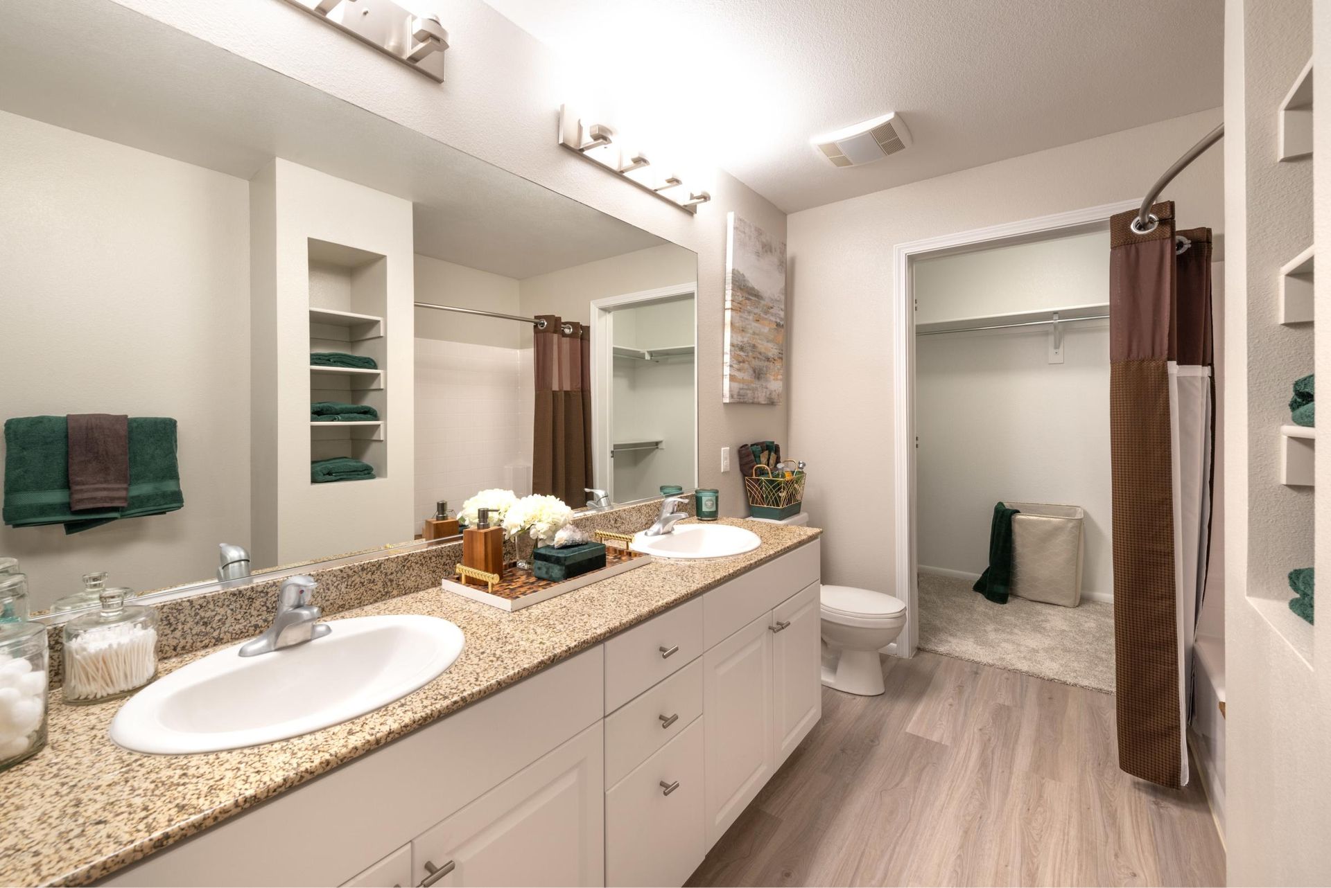 Bathroom in an apartment with a double-sink vanity, granite countertop, large mirror, and a shower.