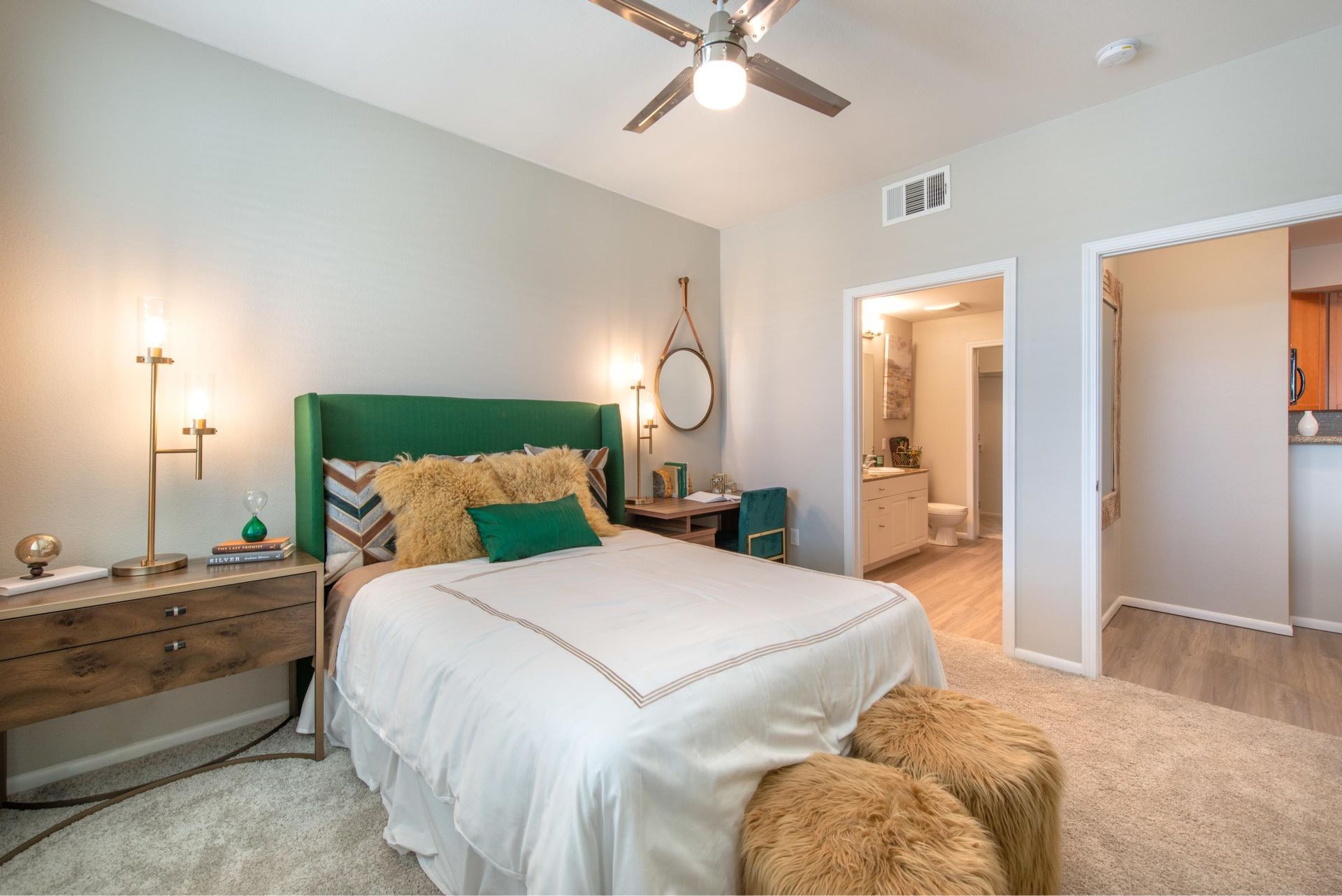 Bedroom with green upholstered headboard, two nightstands, and an open doorway to an ensuite bathroom.