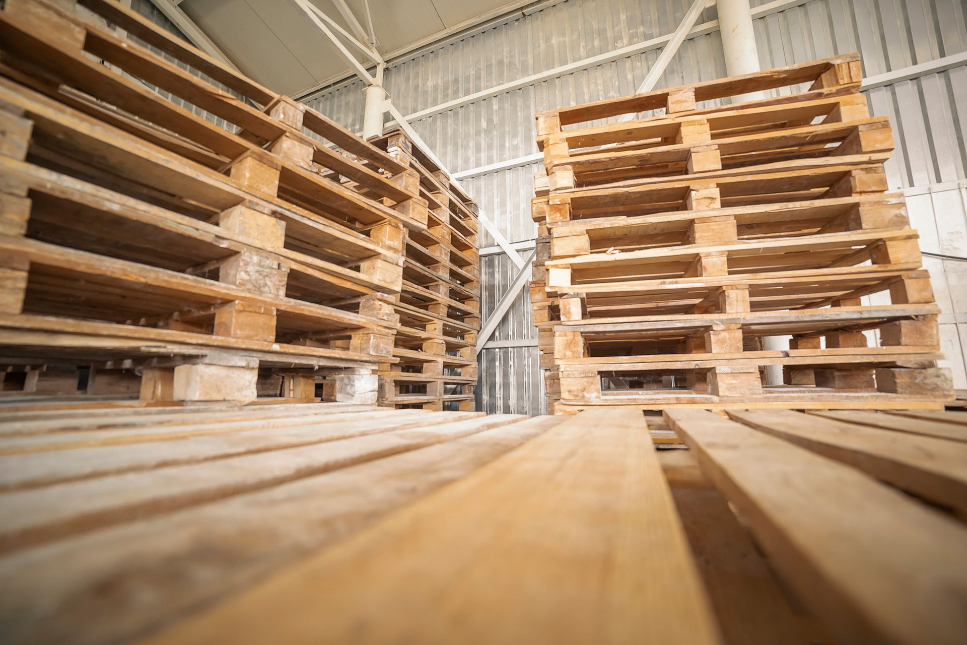 A warehouse filled with lots of wooden pallets stacked on top of each other.