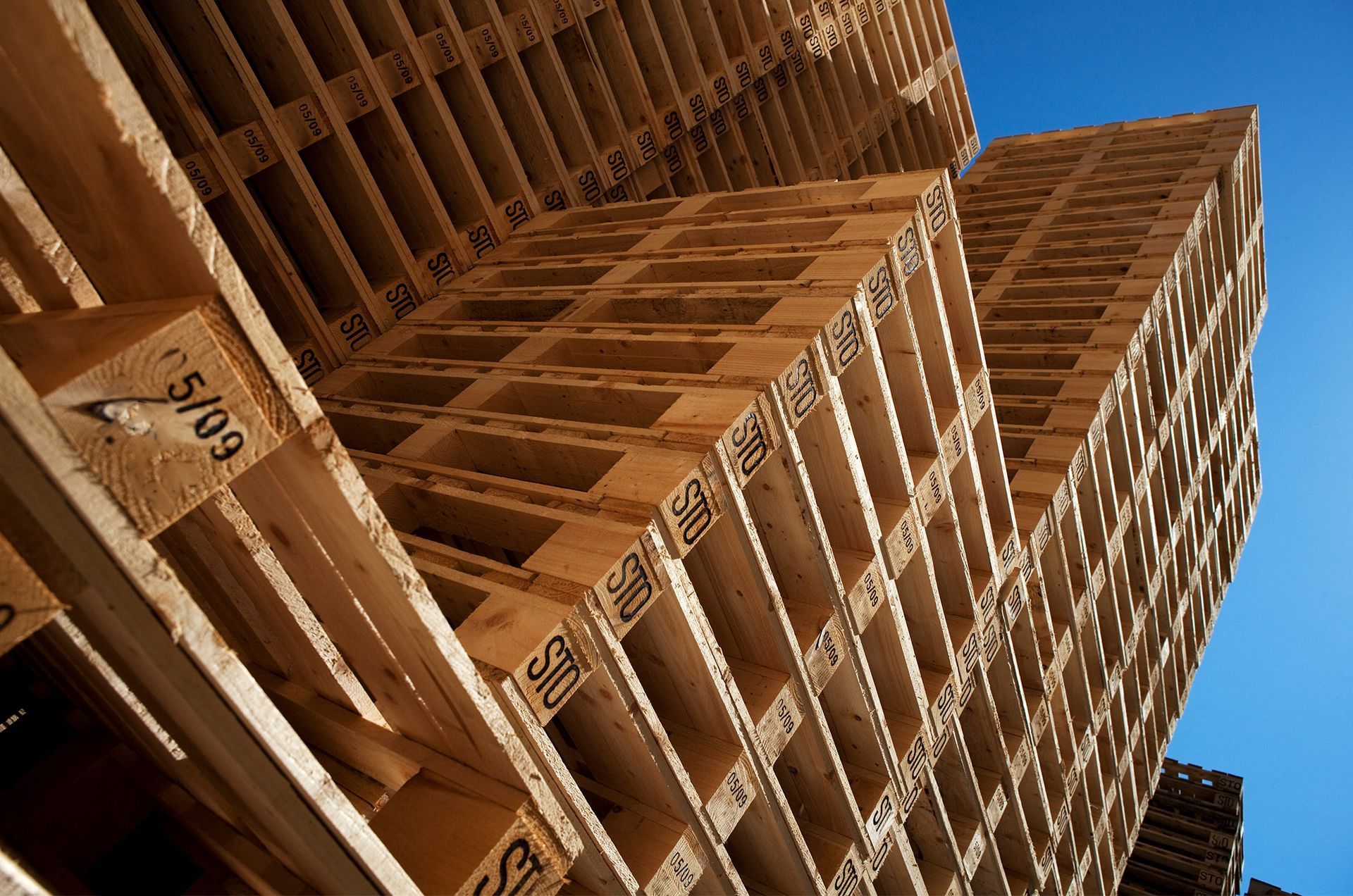 A stack of wooden pallets against a blue sky.