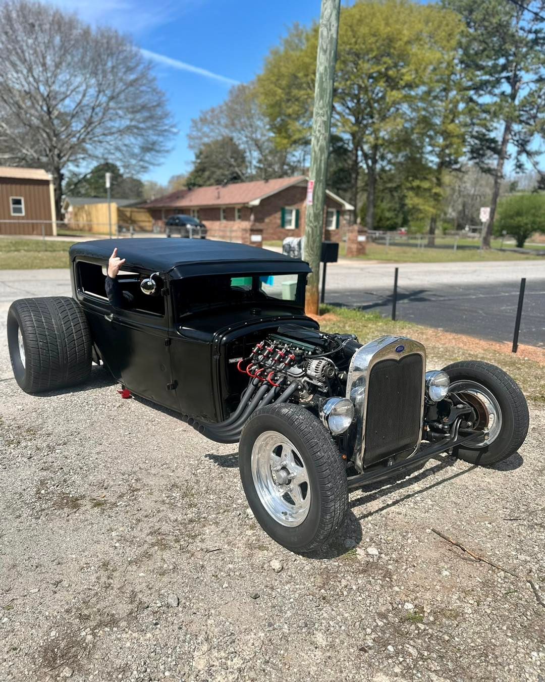 A black hot rod is parked on the side of the road.