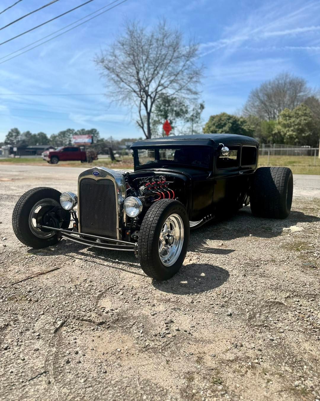 A black hot rod is parked on the side of the road.