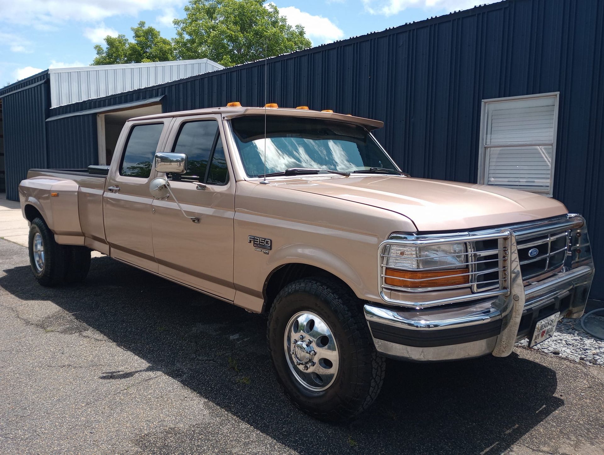 A tan ford truck is parked in front of a blue building.