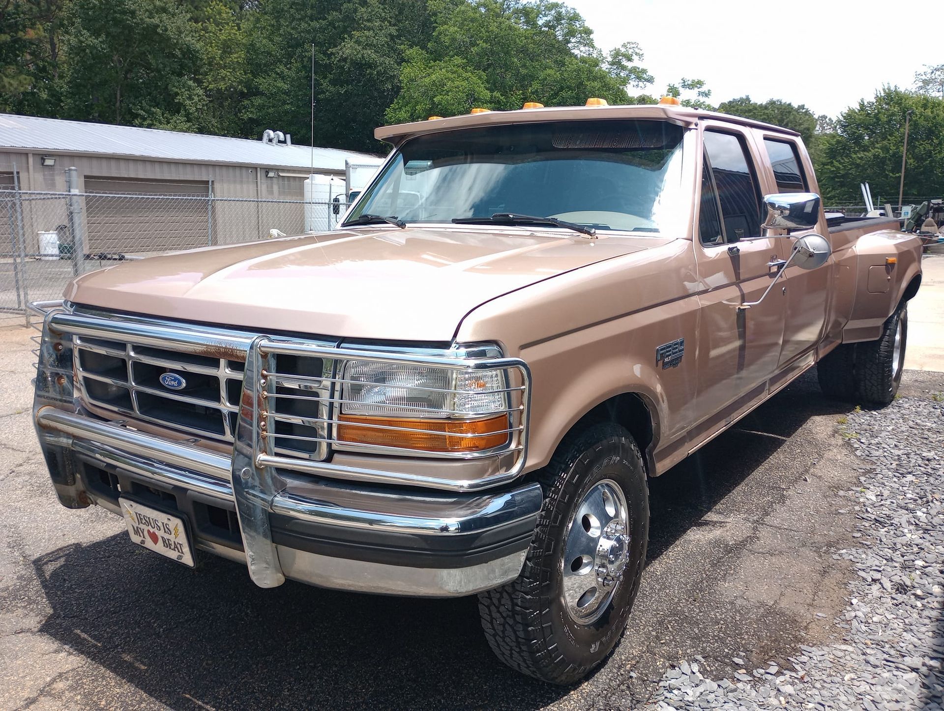 A brown ford truck is parked in a gravel lot.
