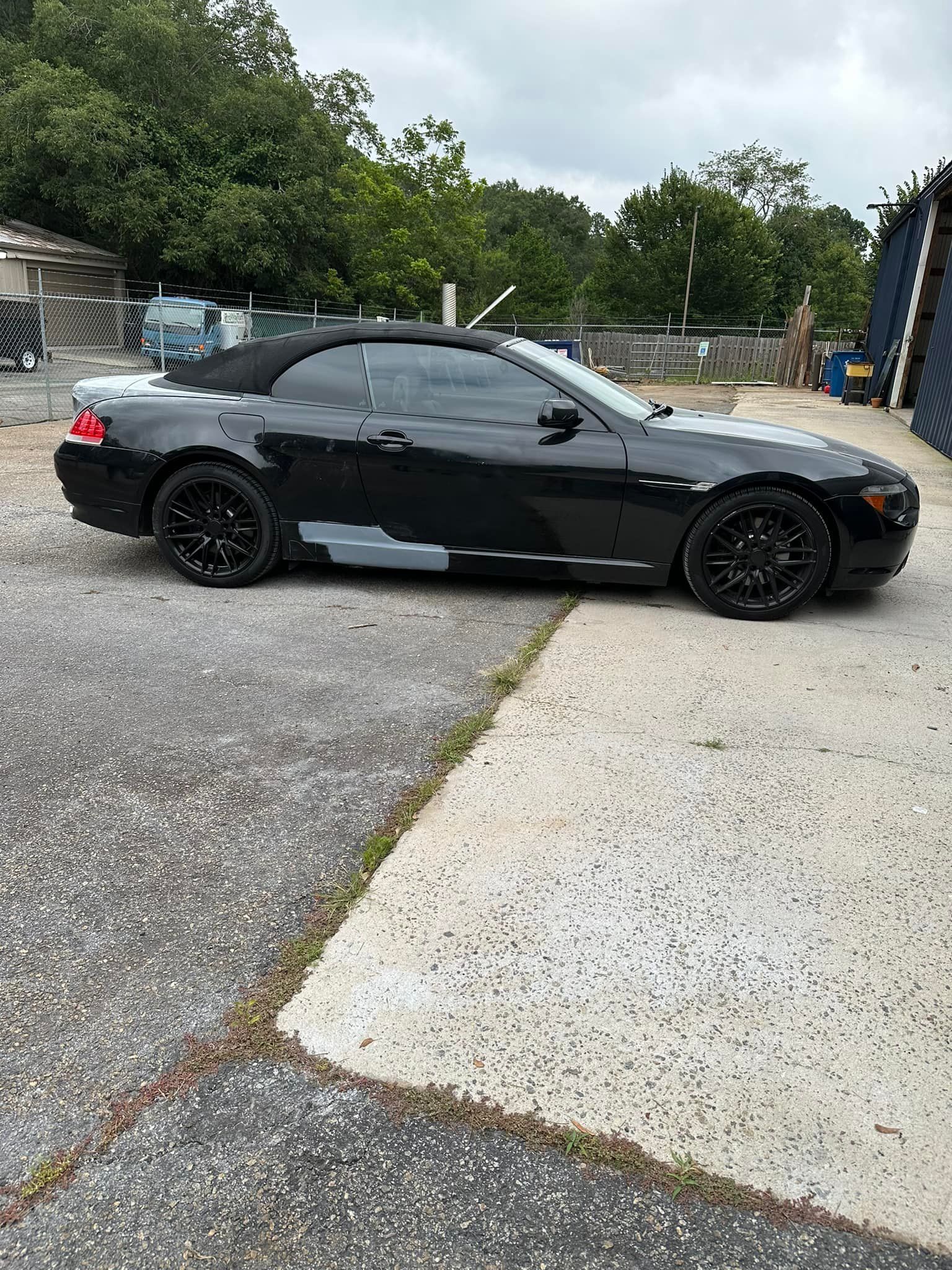 A black bmw 6 series convertible is parked in a parking lot.
