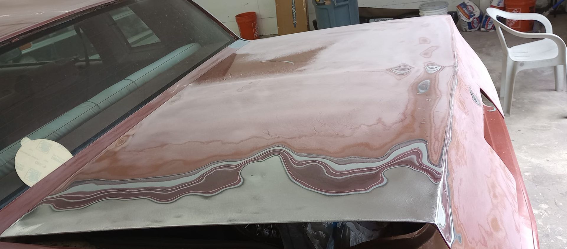 The hood of a car is being repaired in a garage.