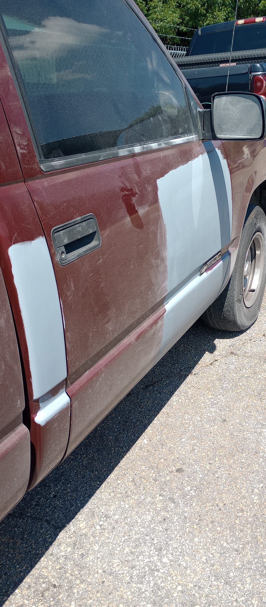 A red truck with white stripes on the side is parked on the side of the road.