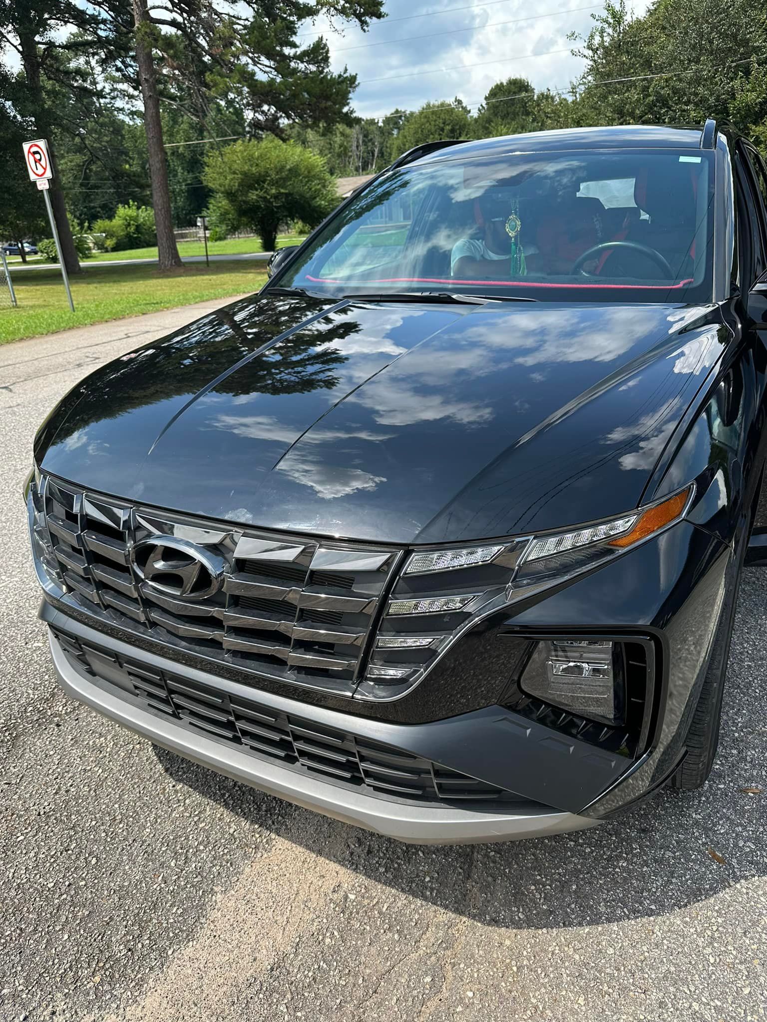 A black hyundai tucson is parked on the side of the road.