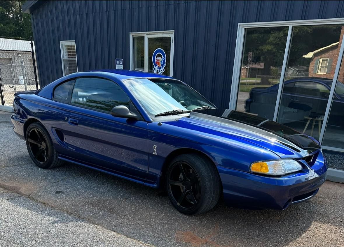 A blue mustang is parked in front of a building.