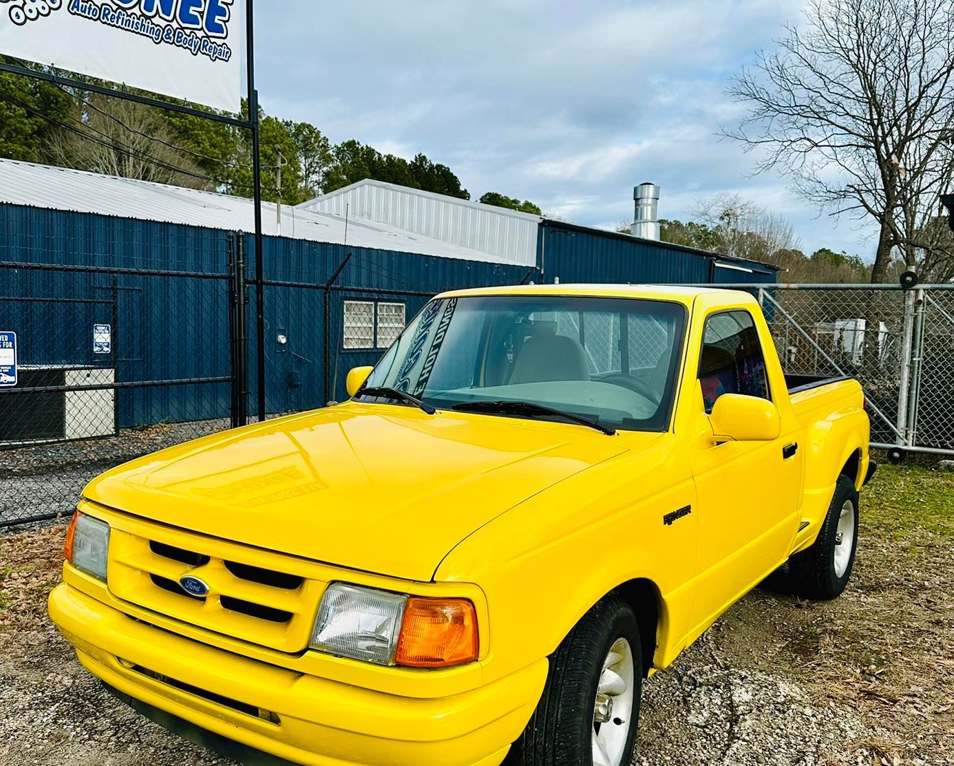 A yellow truck is parked in front of a blue building.