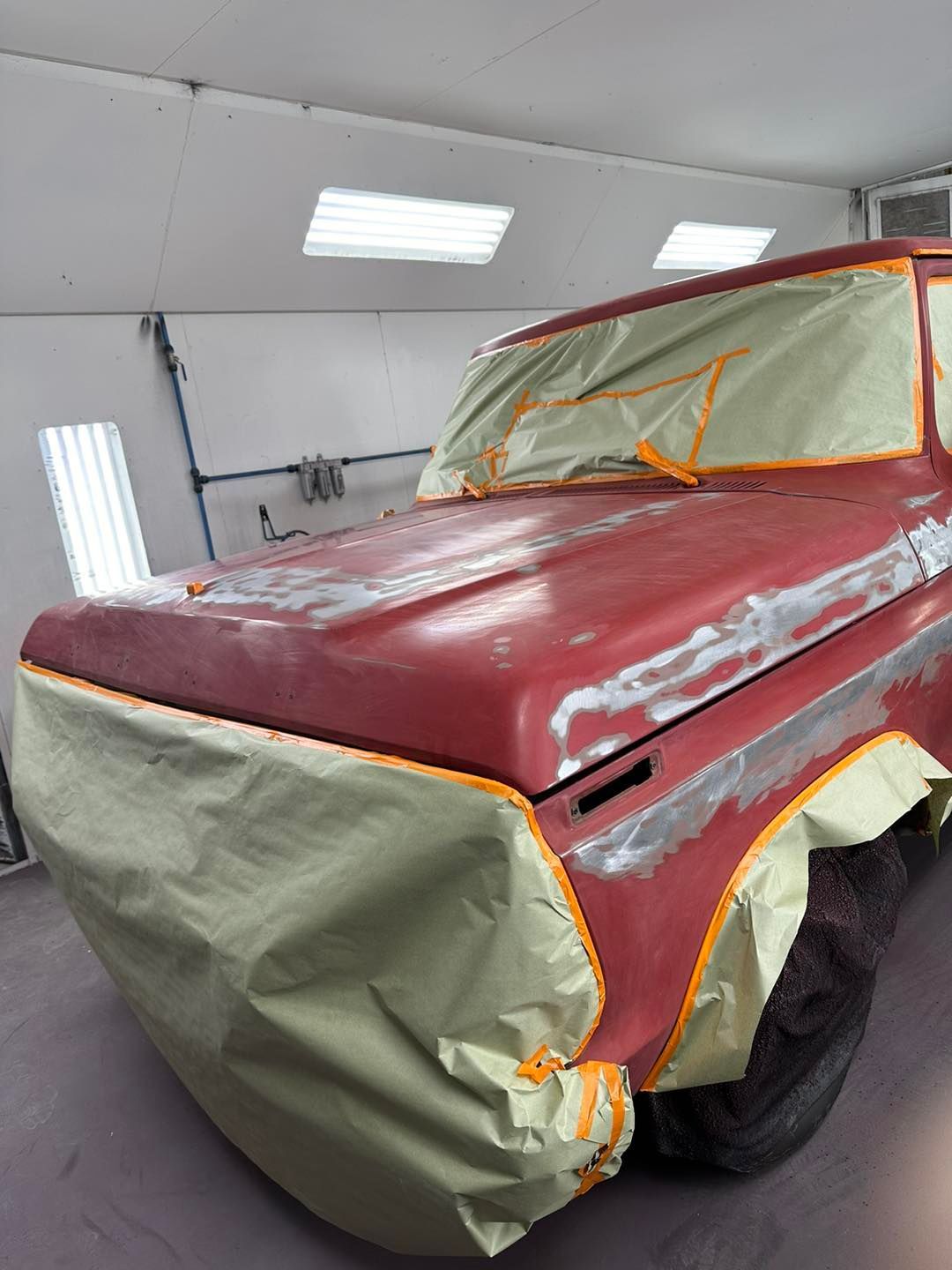 A red truck is being painted in a paint booth.