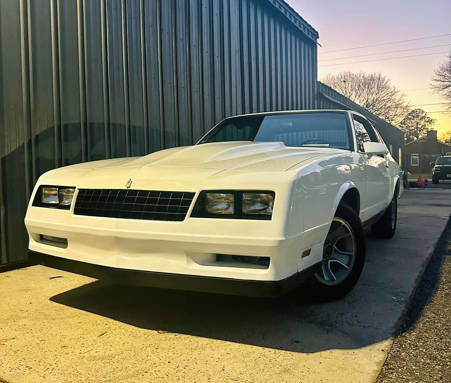 A white car is parked in front of a building.