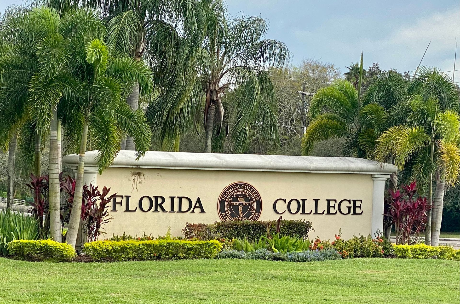 A sign for florida college is sitting in the middle of a lush green field.