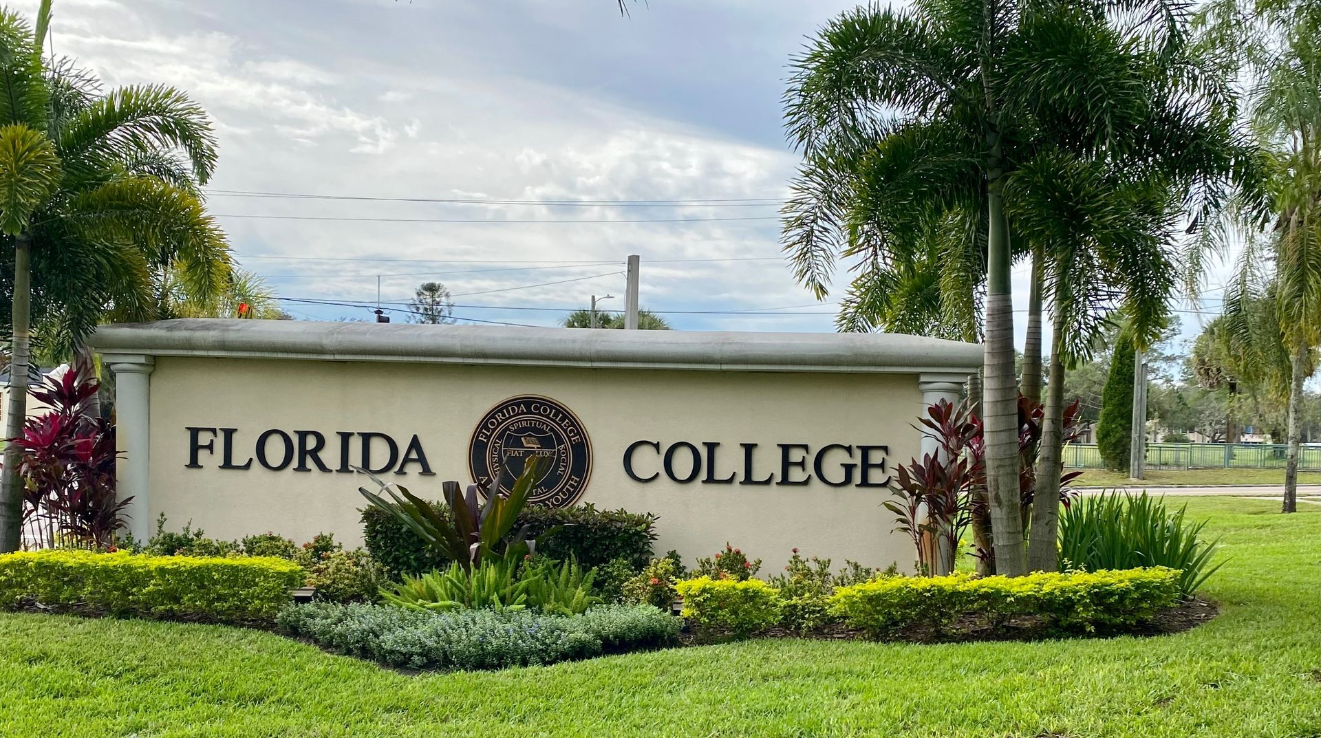 A sign for florida college is surrounded by trees and bushes.