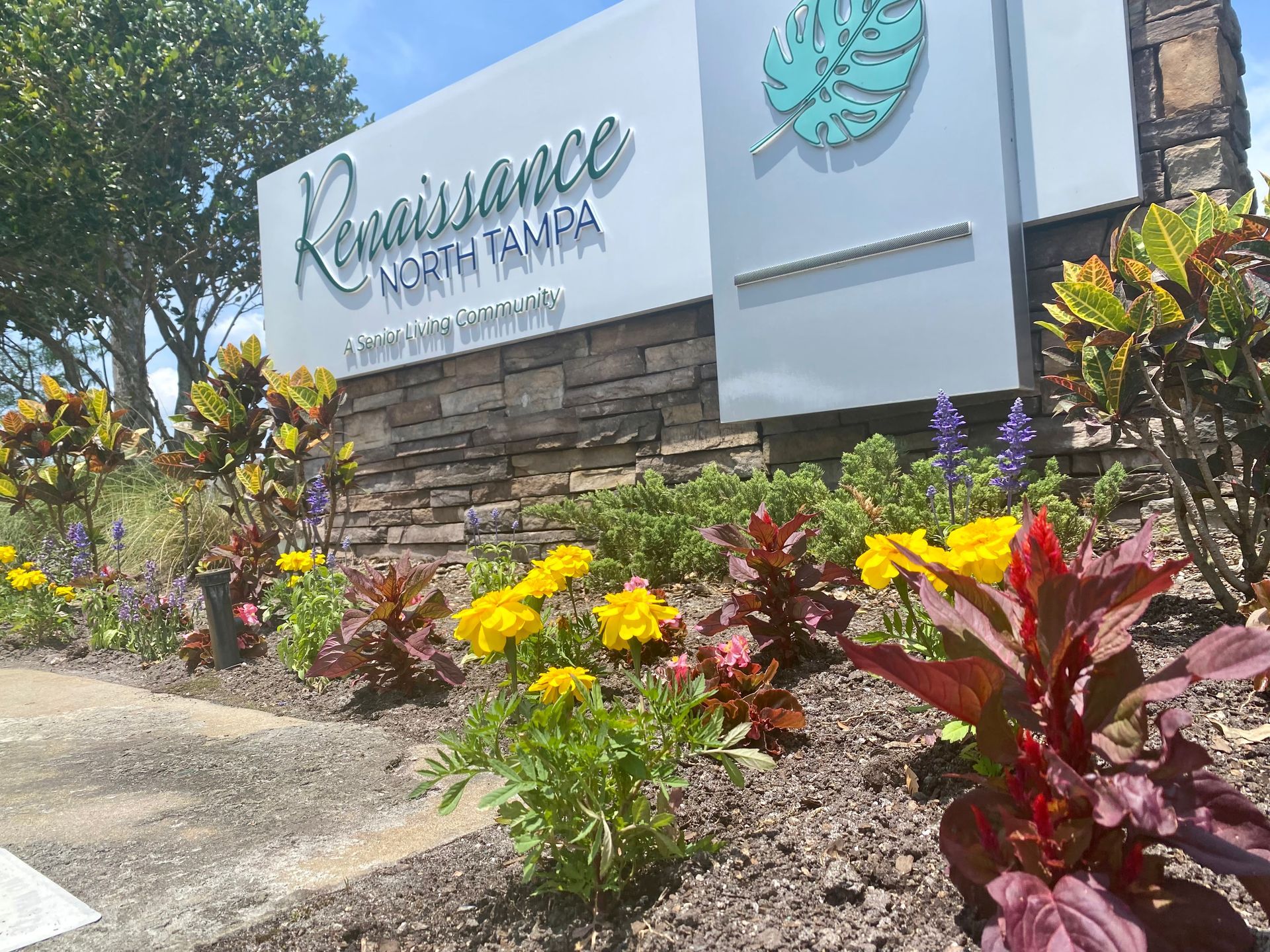 A sign for renaissance north tampa is surrounded by flowers.