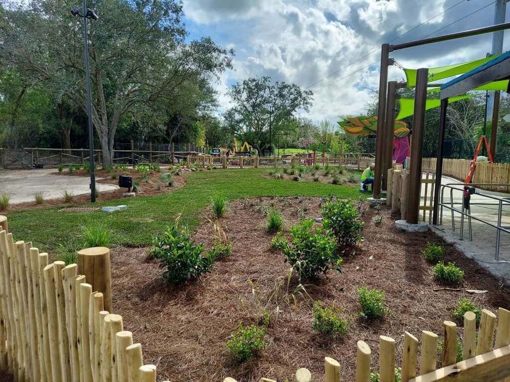 A wooden fence surrounds a playground in a park.