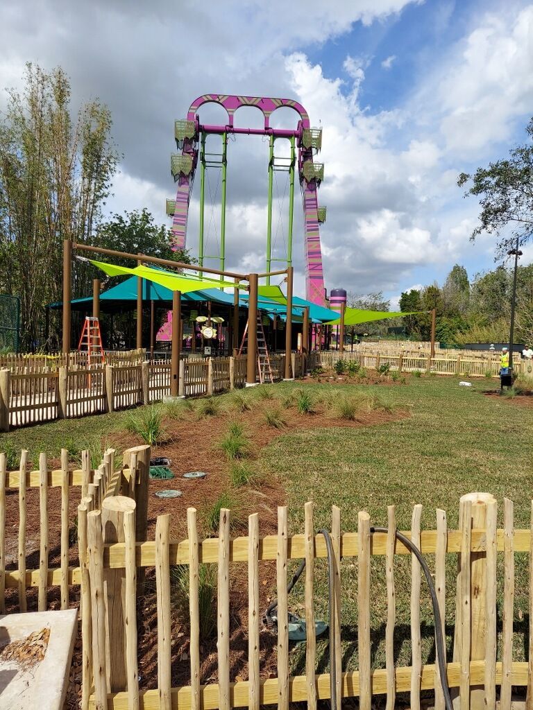 A roller coaster is behind a wooden fence in a park.-Crowders Landscaping