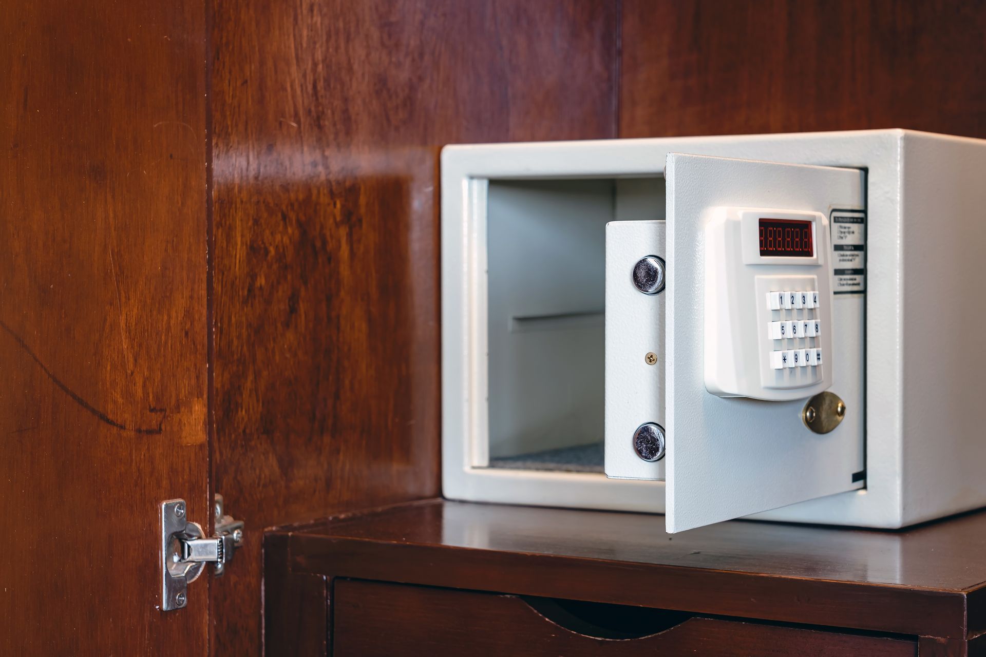 A safe is open and sitting on top of a wooden dresser.