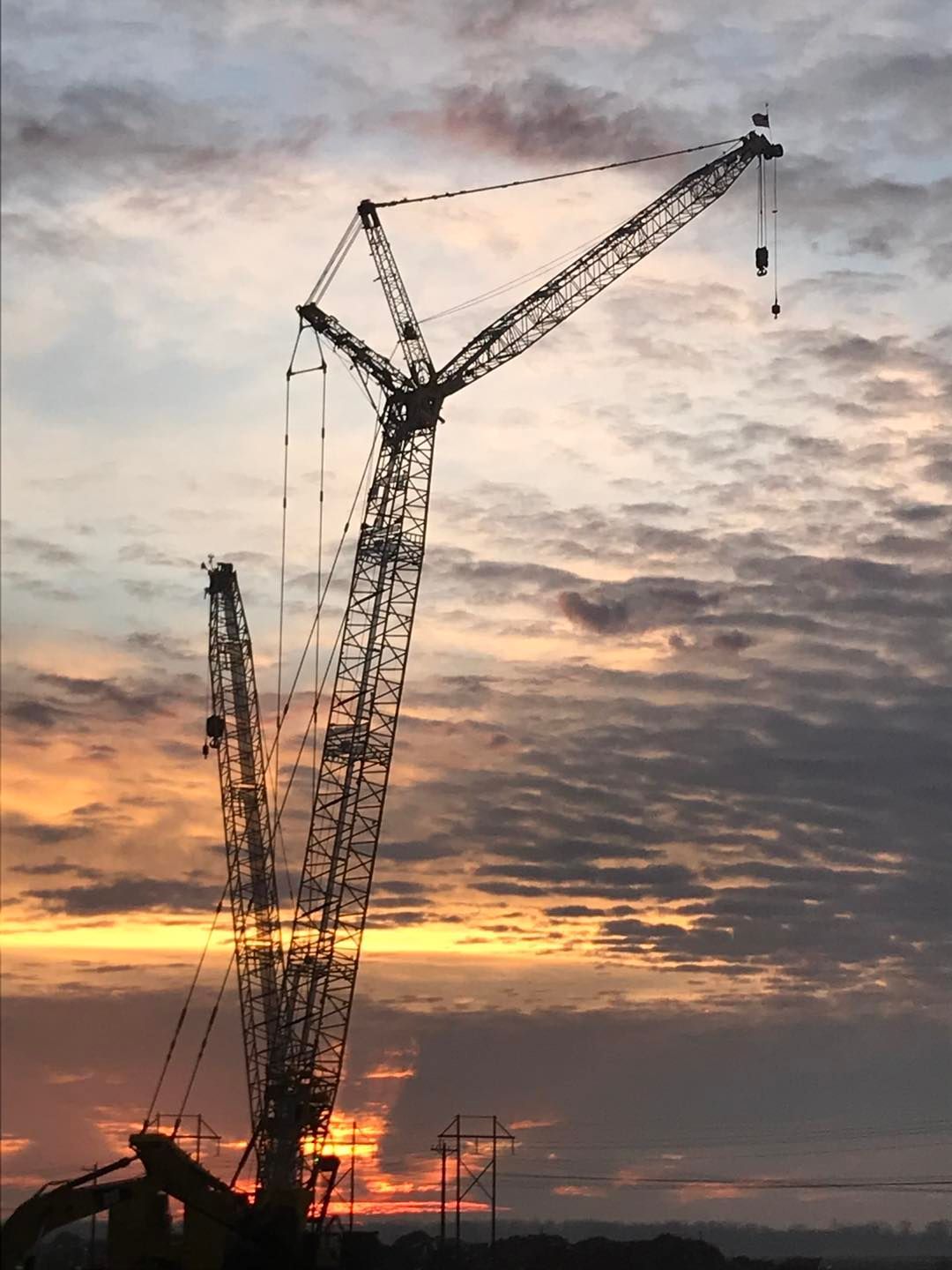 A large crane is silhouetted against a sunset sky