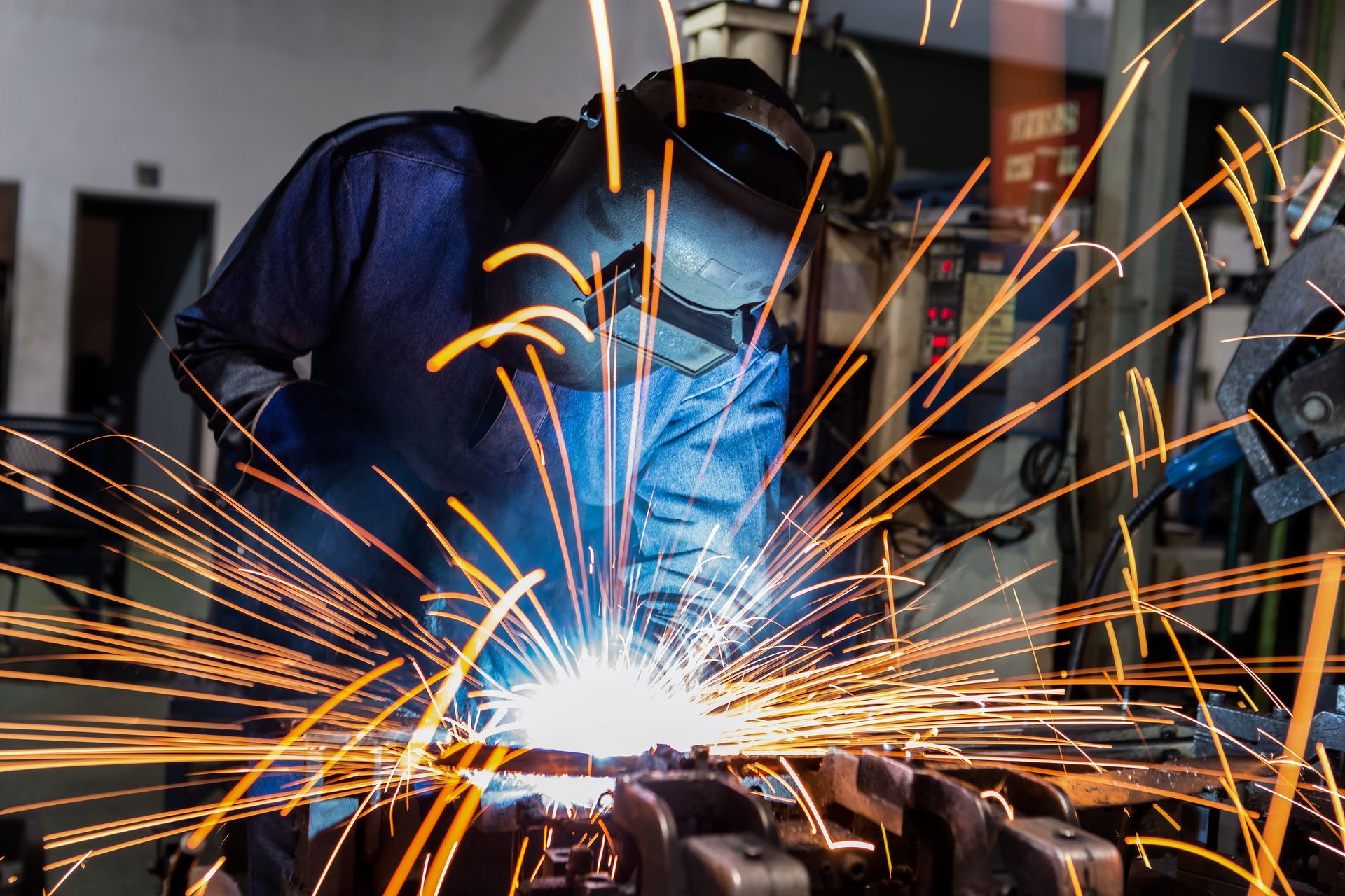 A man is welding a piece of metal in a factory.