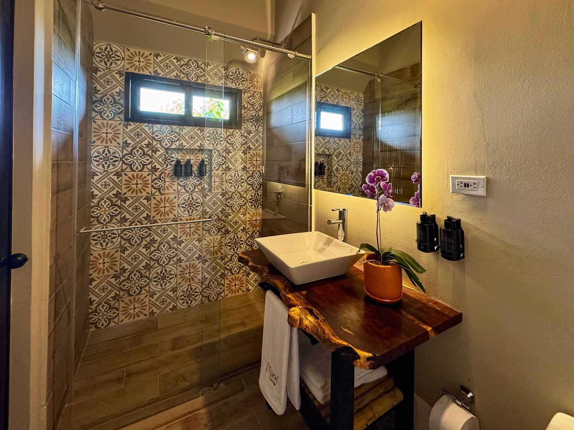 Un baño con lavabo, espejo y ducha.