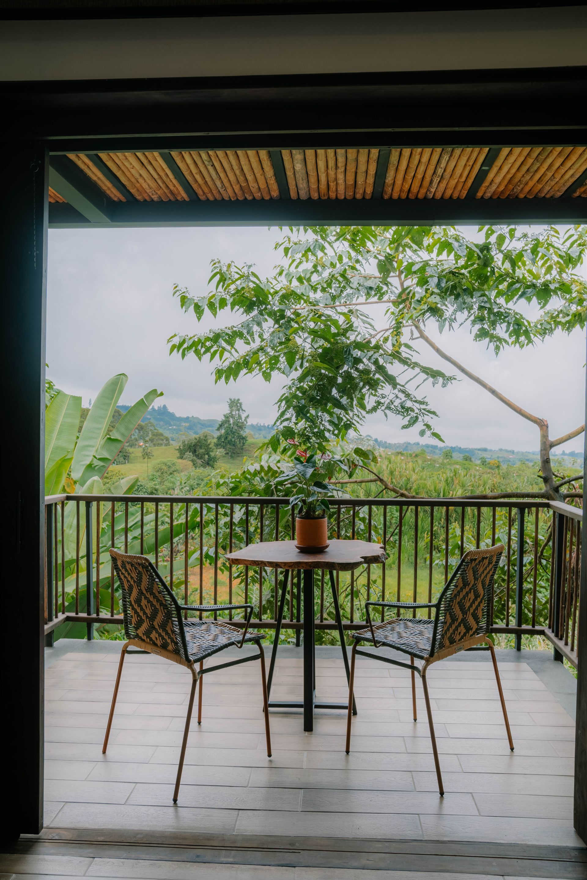 Un balcón con mesa y sillas y vista a un bosque.
