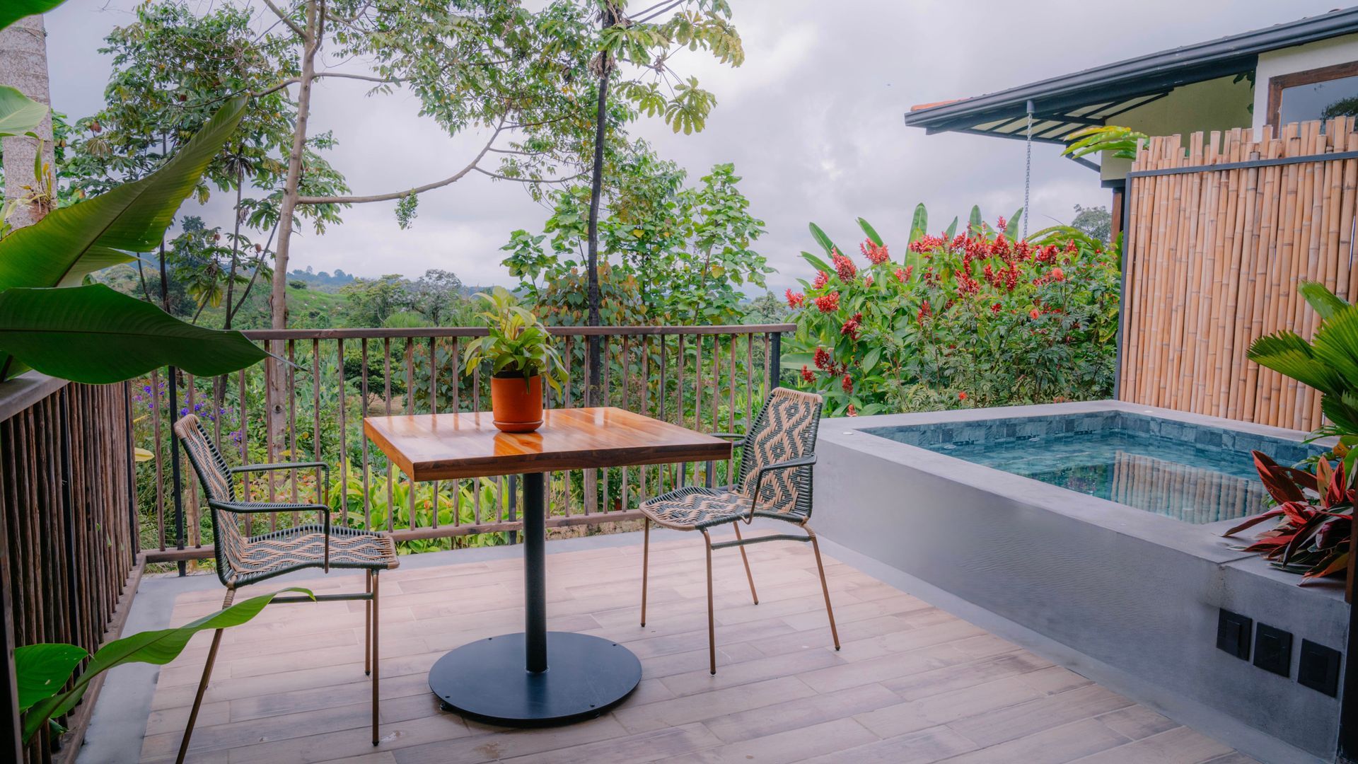Una mesa y sillas en un balcón con vistas a una piscina.