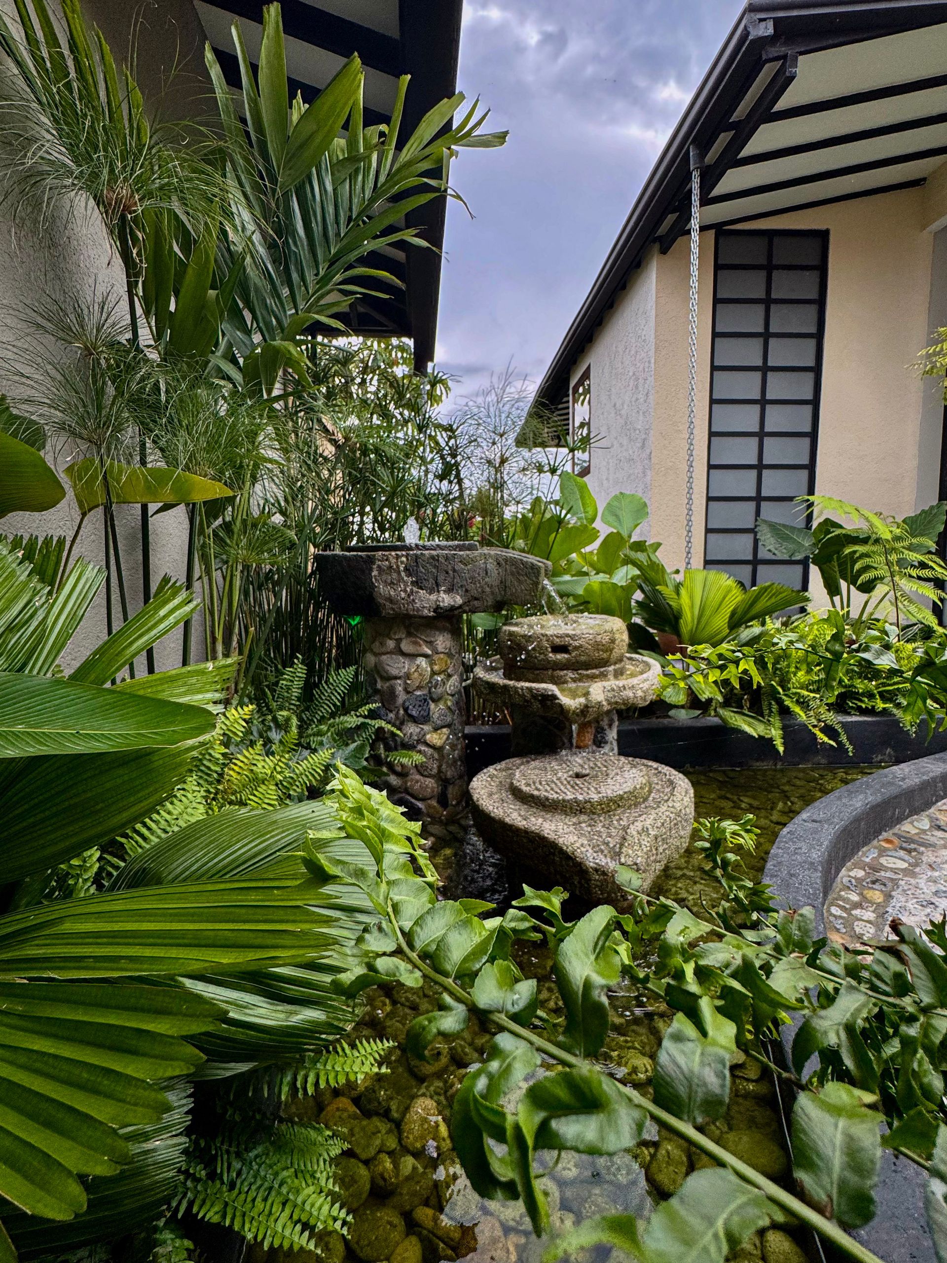 Un jardín con un estanque y una fuente delante de una casa.