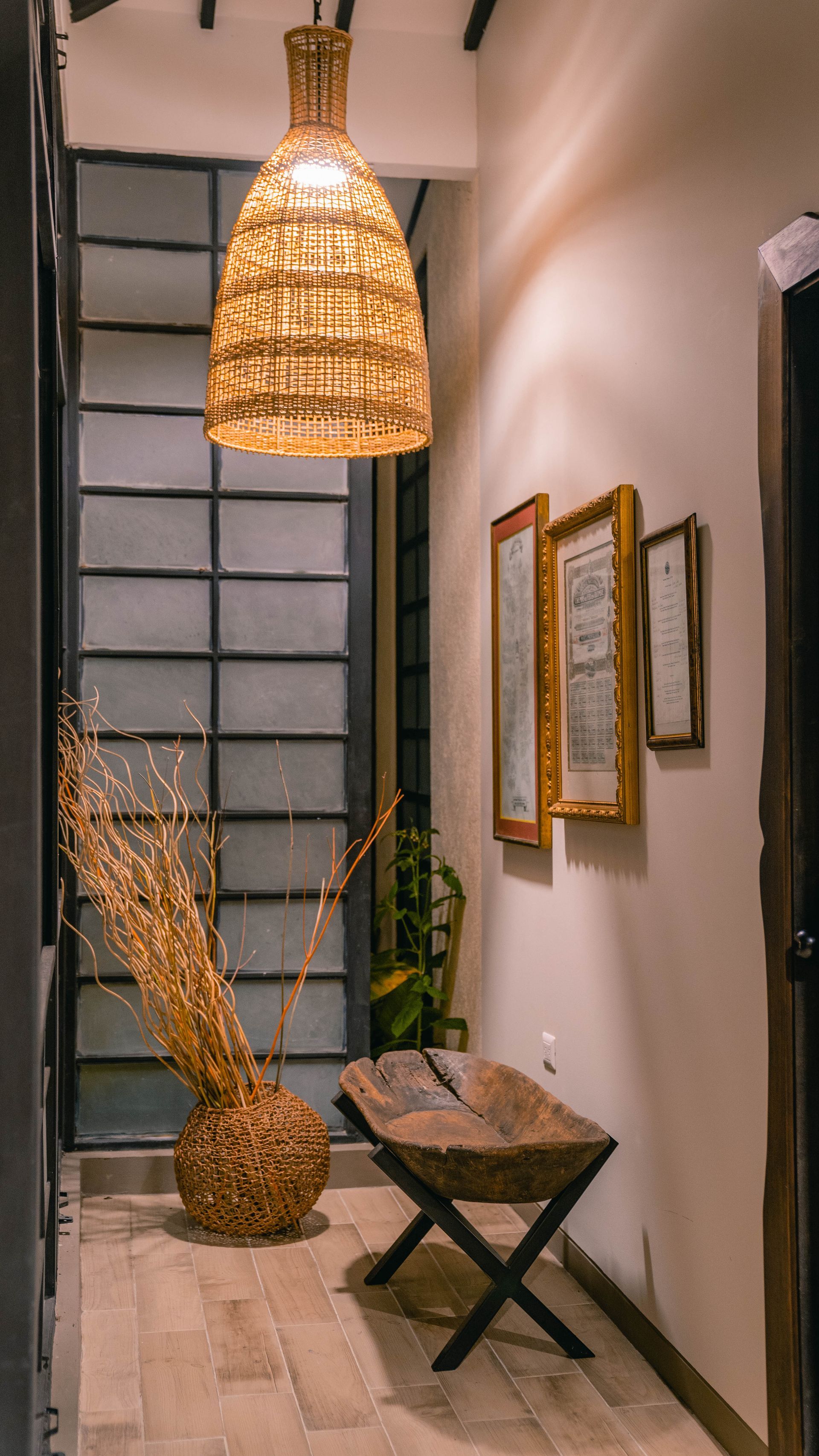 Un pasillo con una lámpara de mimbre colgando del techo y un banco de madera.