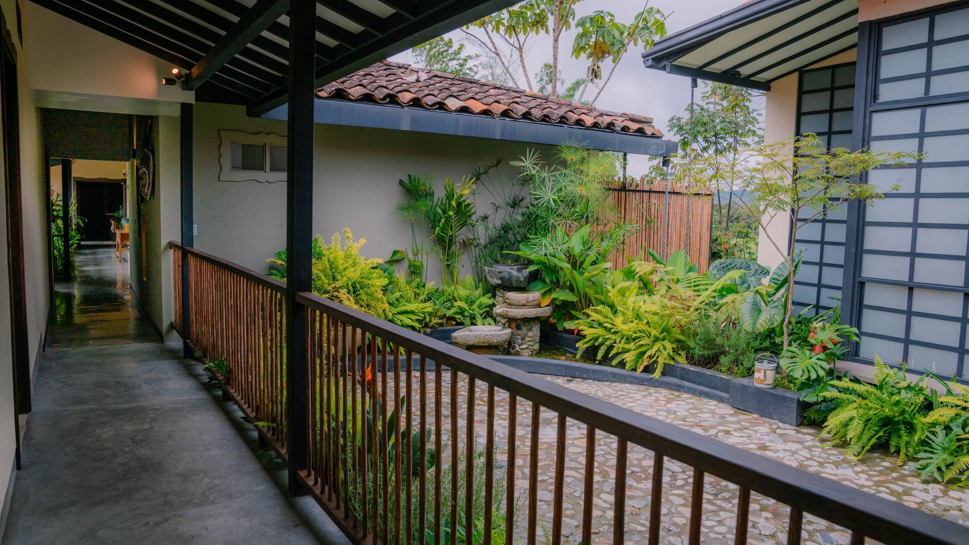 Un largo pasillo con barandilla que conduce a un jardín.