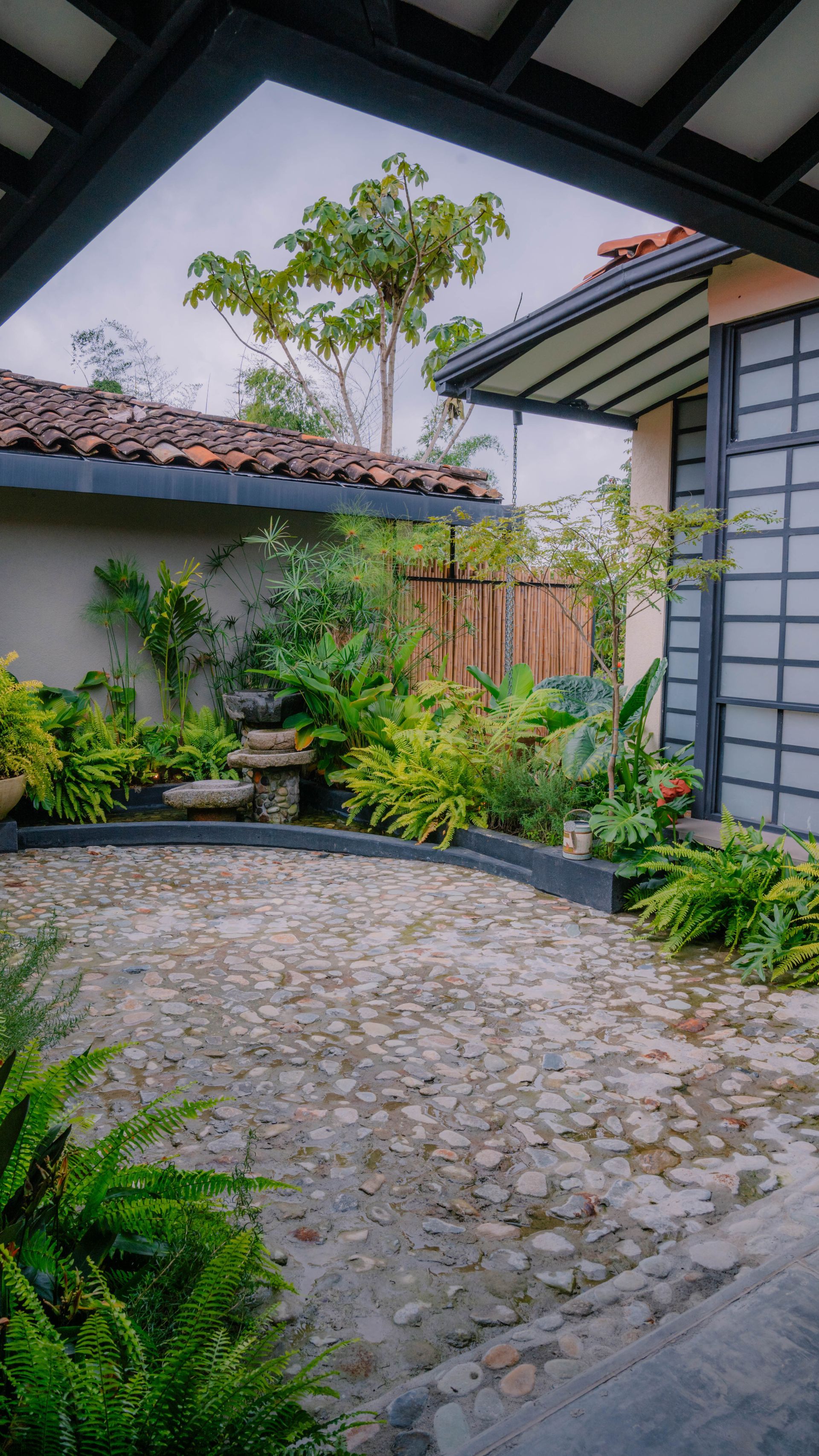Un camino de piedra que conduce a una casa rodeada de plantas y árboles.