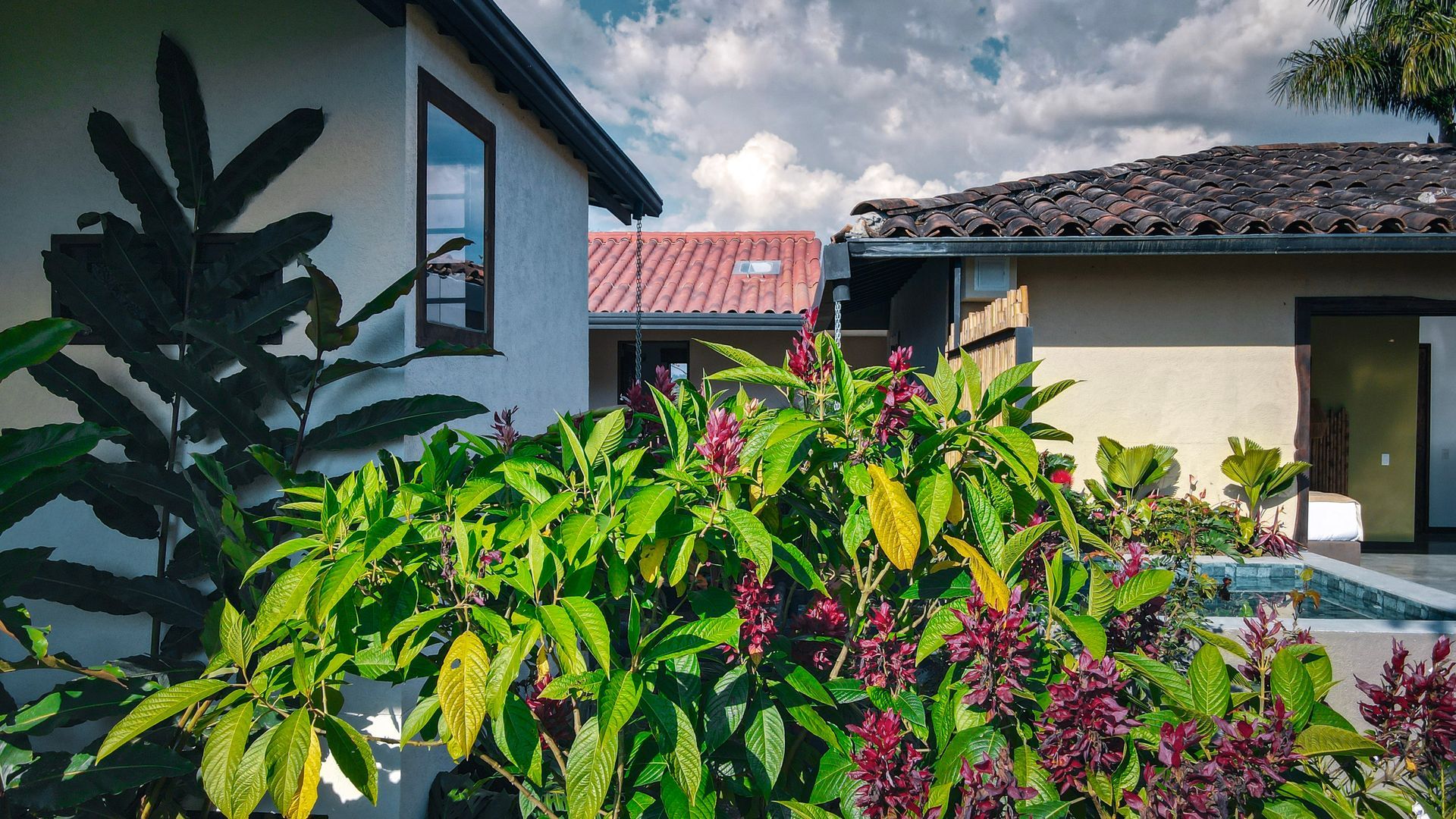Una casa con techo de tejas rojas está rodeada de flores y plantas.