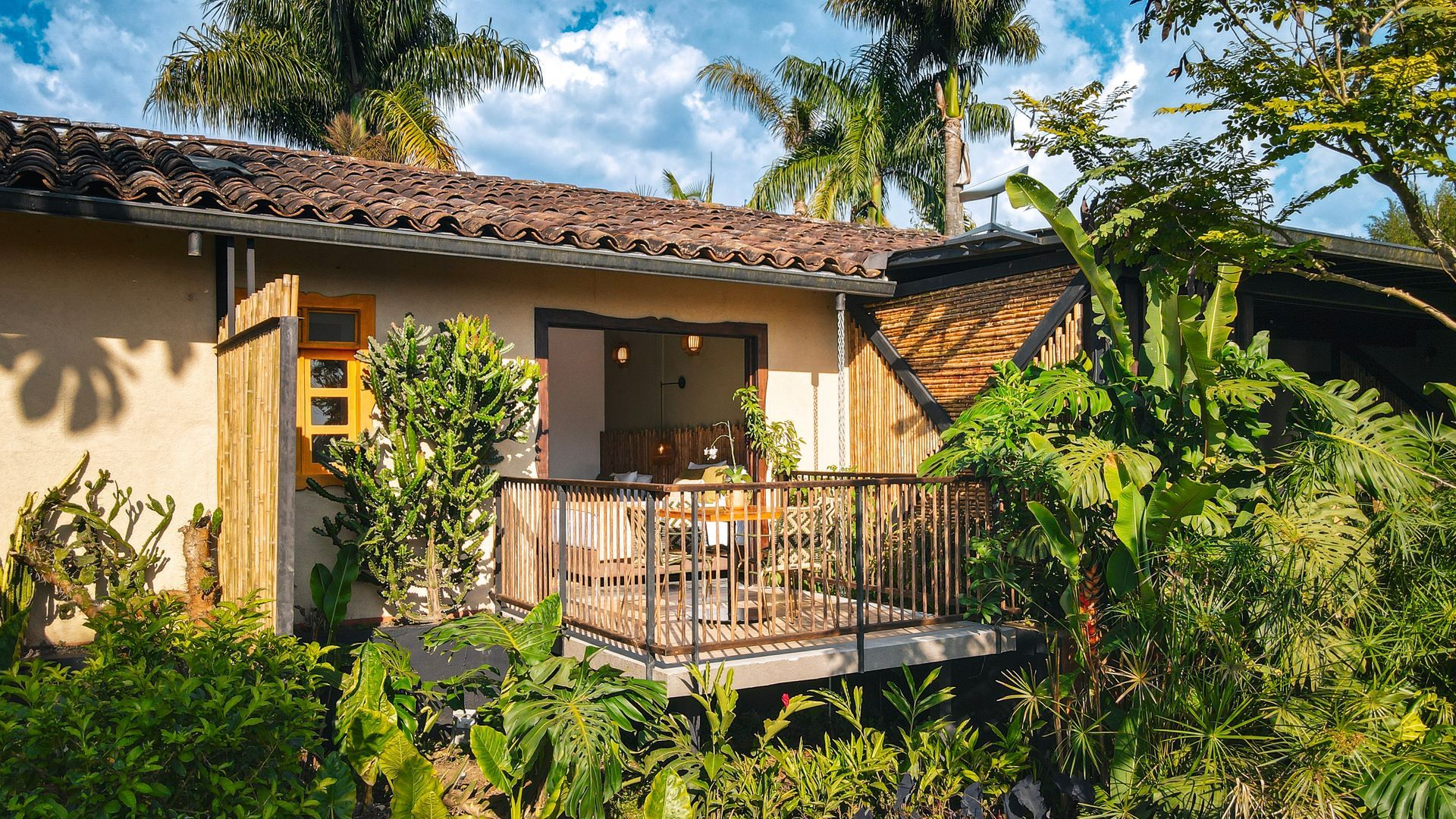 Una pequeña casa con balcón en medio de un exuberante bosque verde.