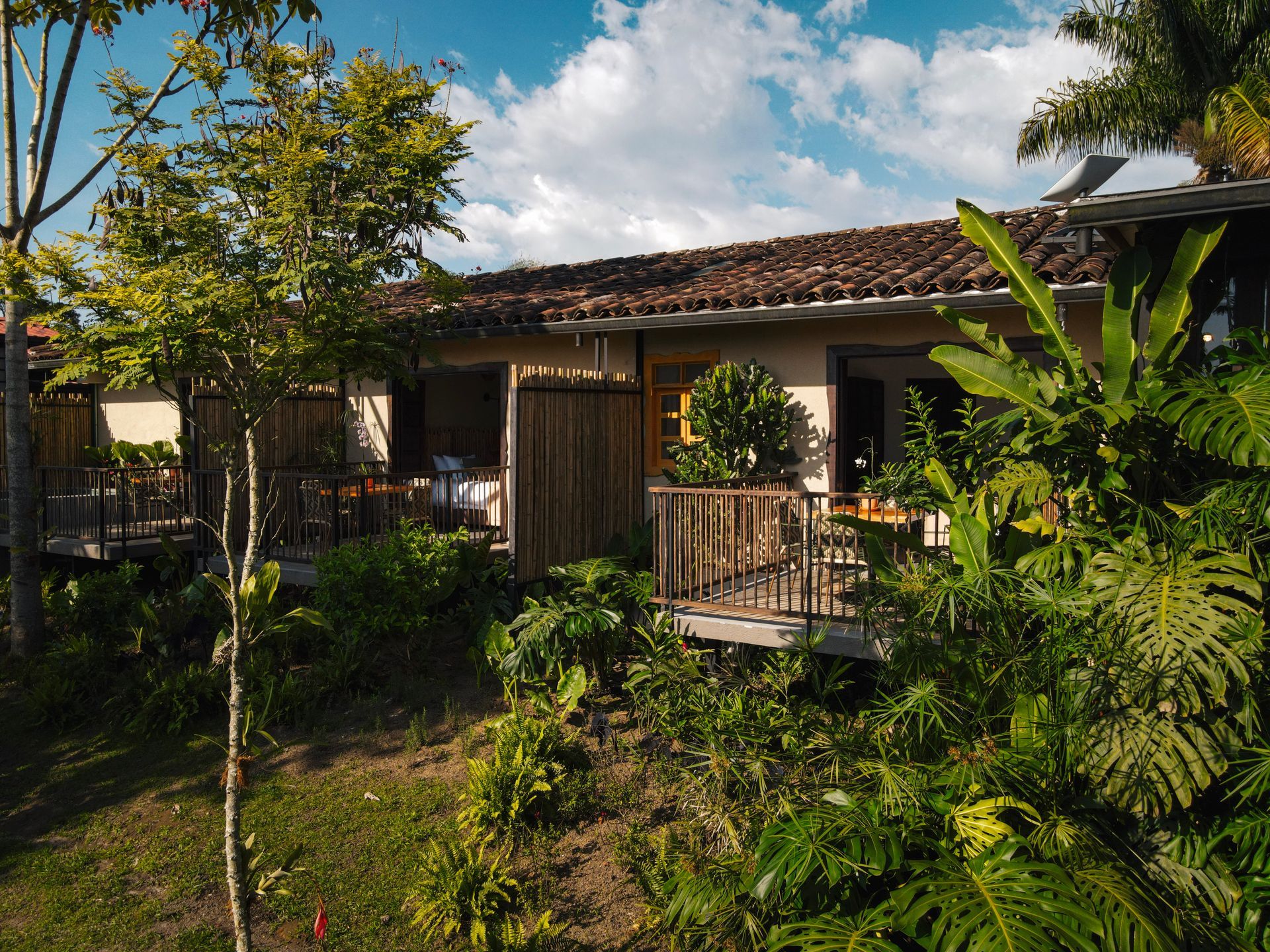 Una casa con balcón rodeada de árboles y arbustos.