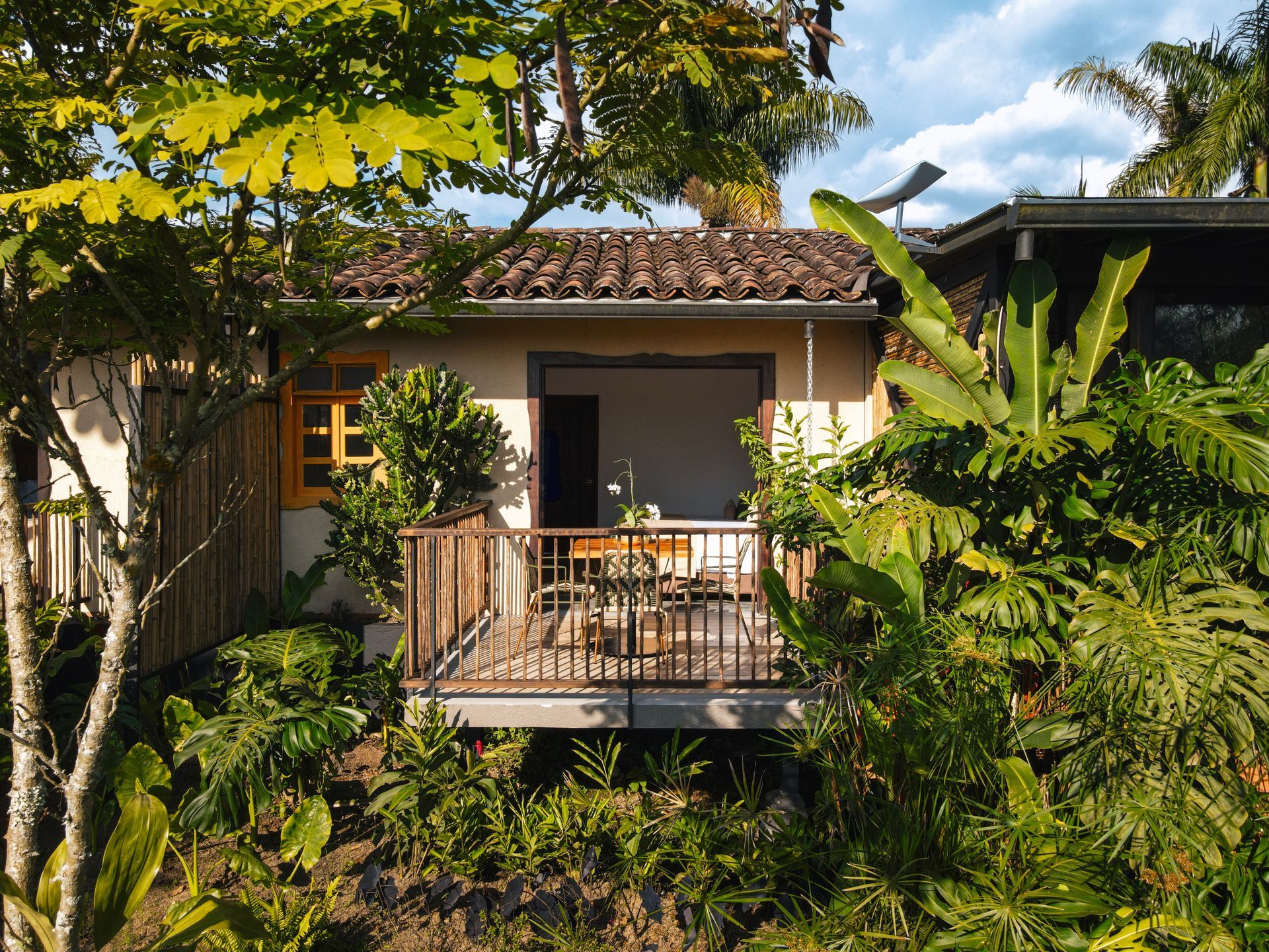 Una pequeña casa con balcón rodeada de árboles.
