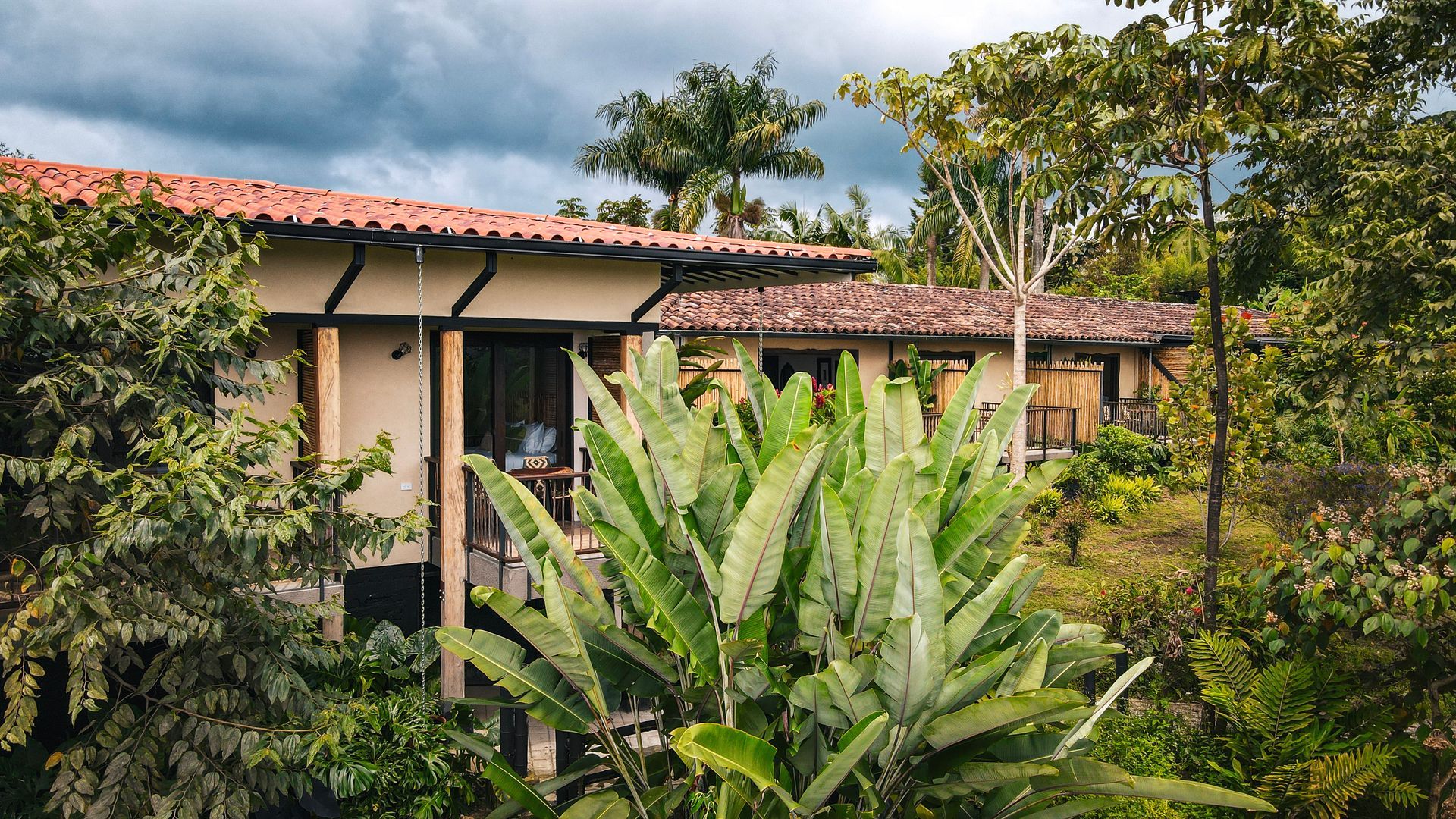 Una casa con techo de tejas rojas está rodeada de árboles y plantas.