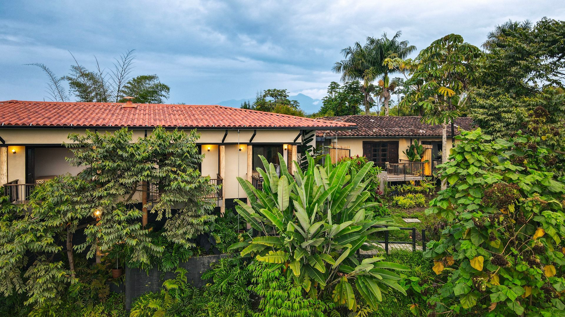 Una casa con techo de tejas rojas está rodeada de árboles y arbustos.