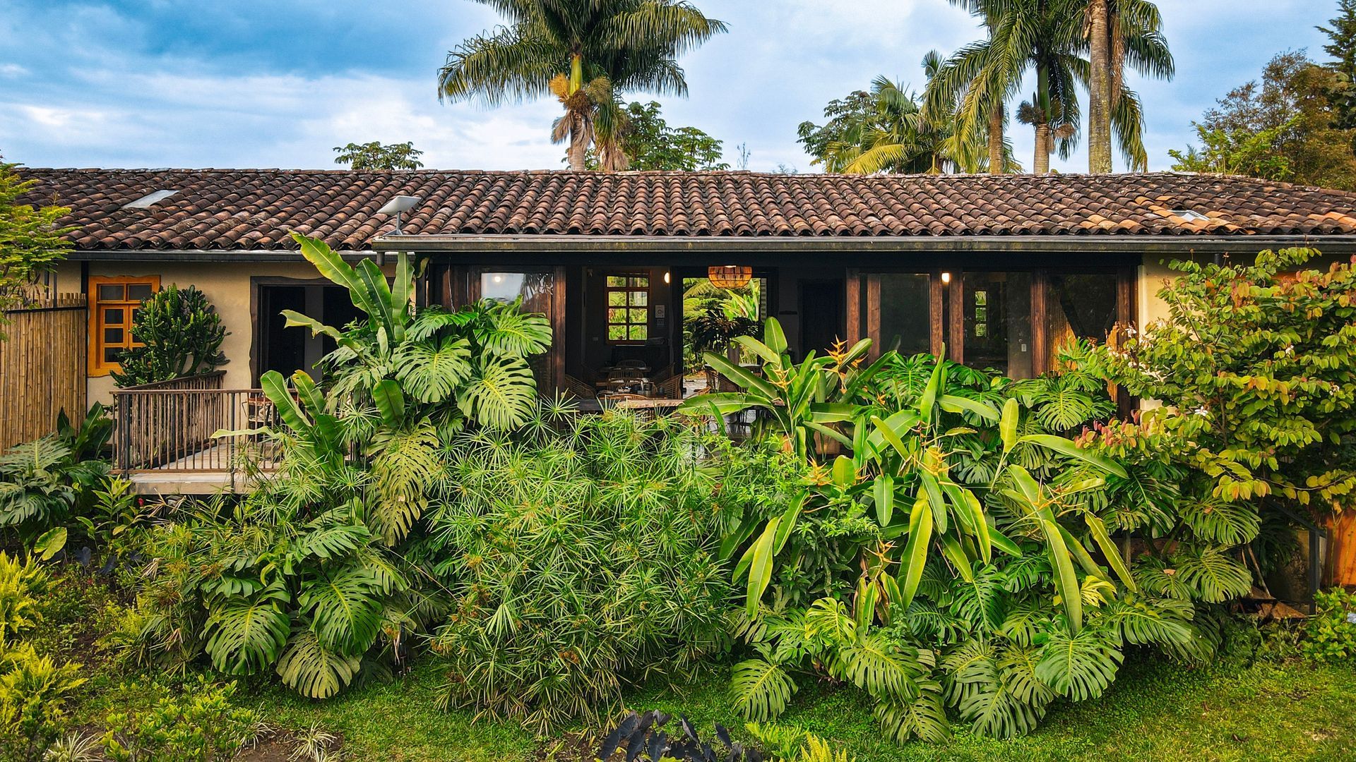 Una casa con techo de tejas está rodeada de árboles y arbustos.
