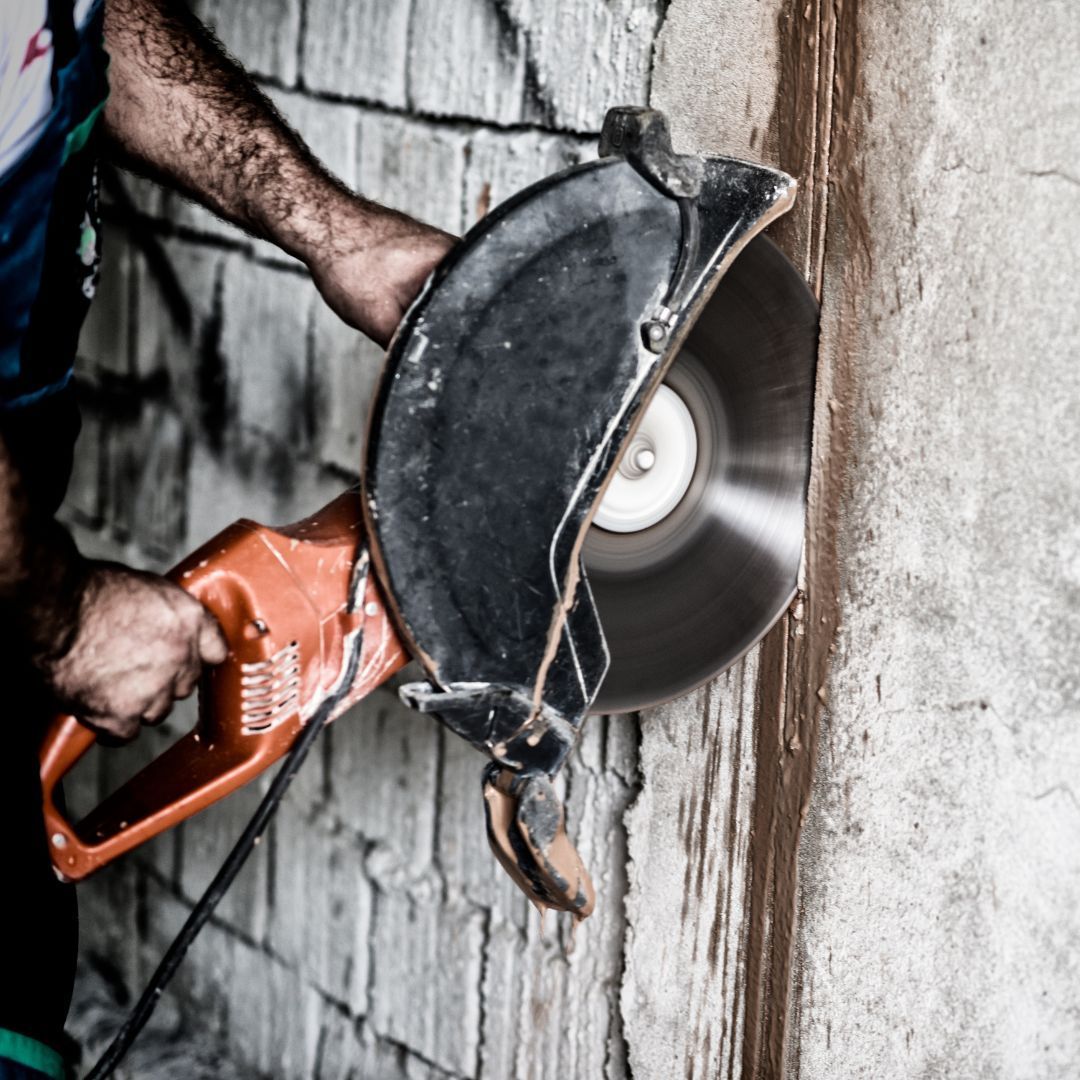 A man is using a circular saw to cut a hole in a wall