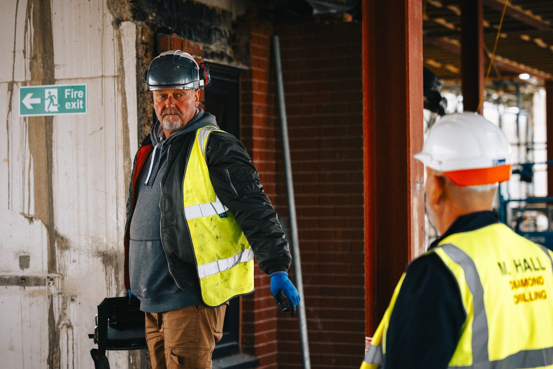 Two construction workers are standing next to each other on a construction site.