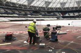 A construction worker is working on the floor of a stadium.