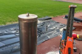 A person is using a machine to cut a hole in a soccer field.