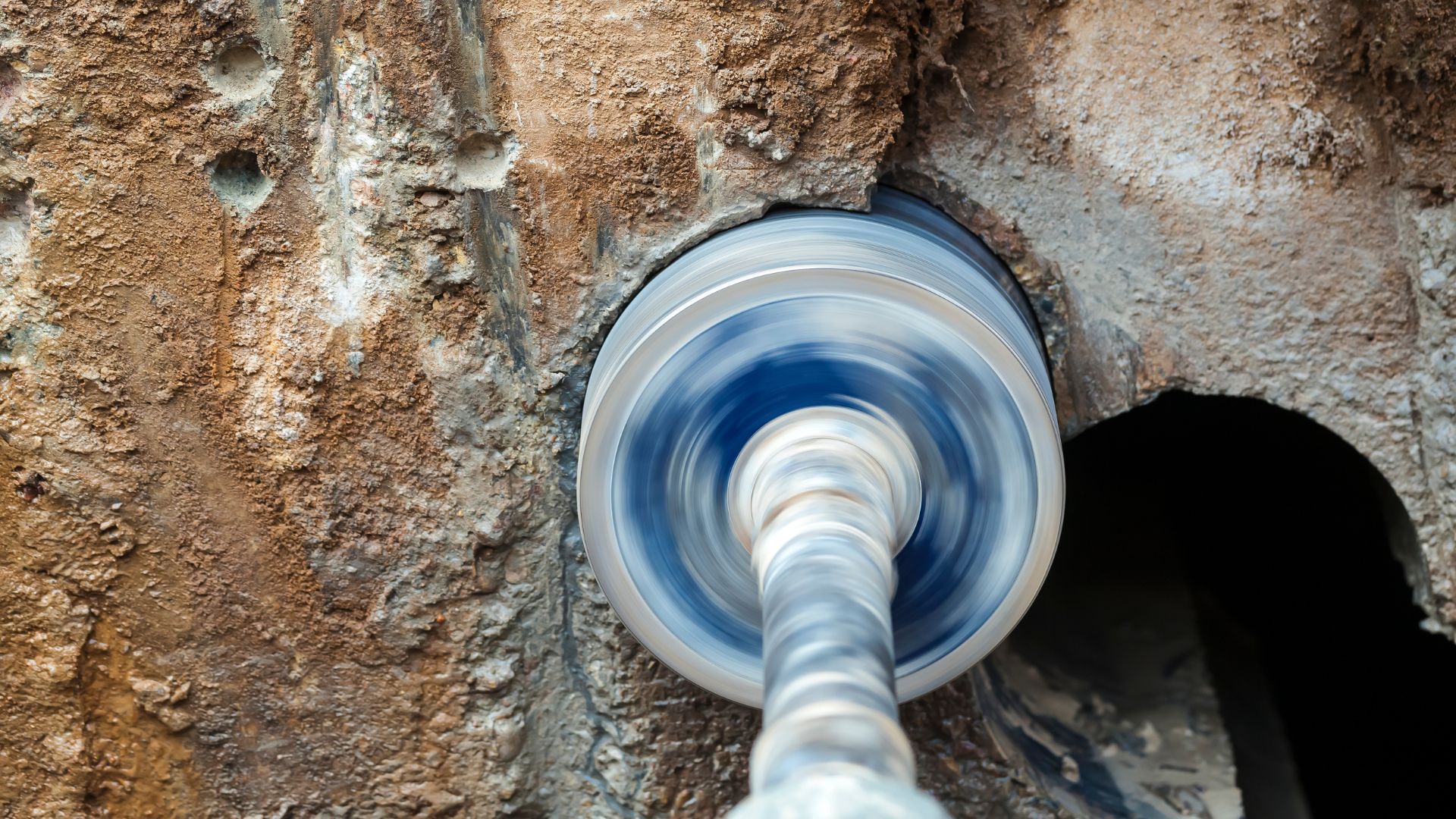 A drill bit is being used to drill a hole in a concrete wall.