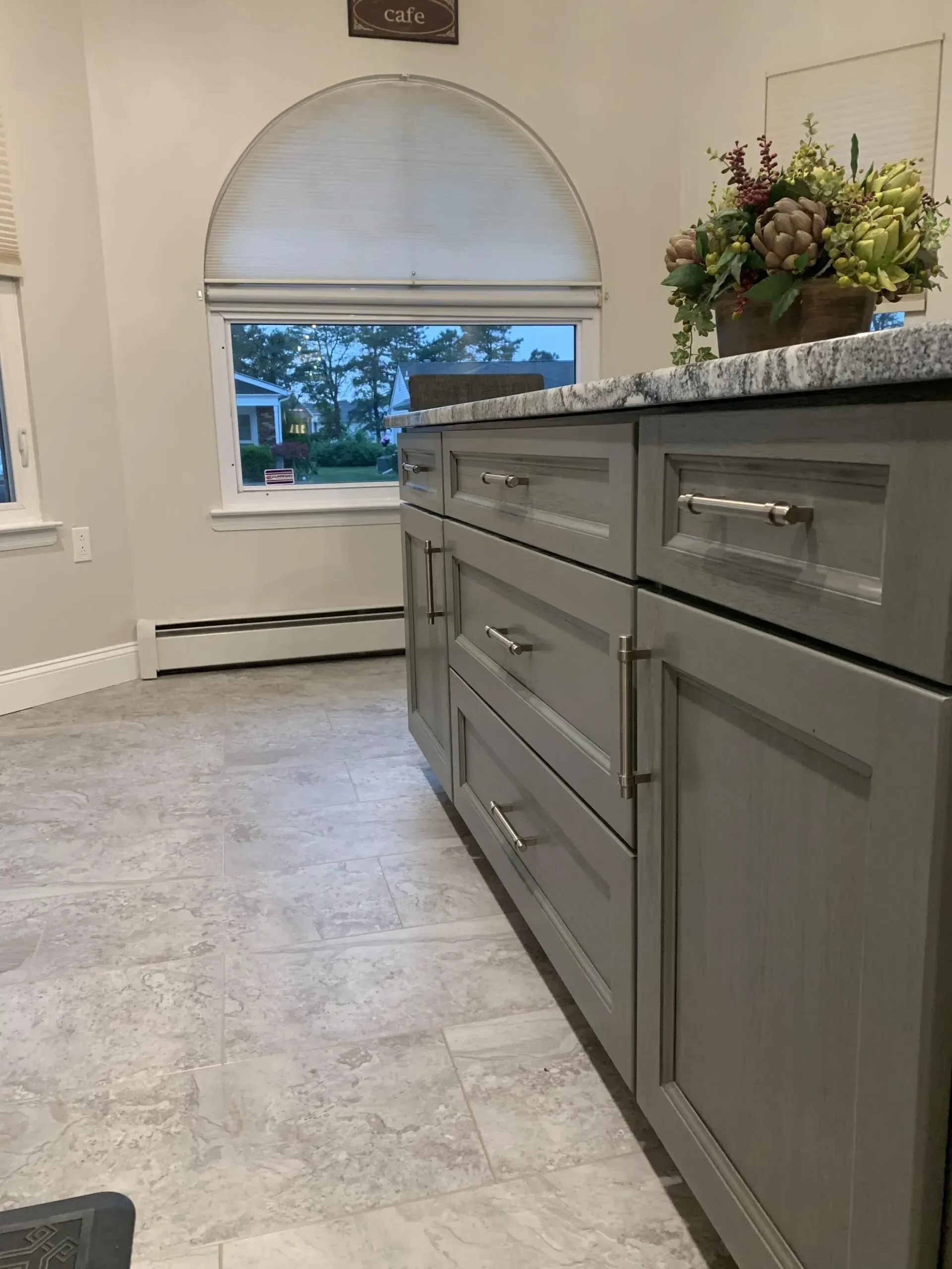 A kitchen with gray cabinets and a window.