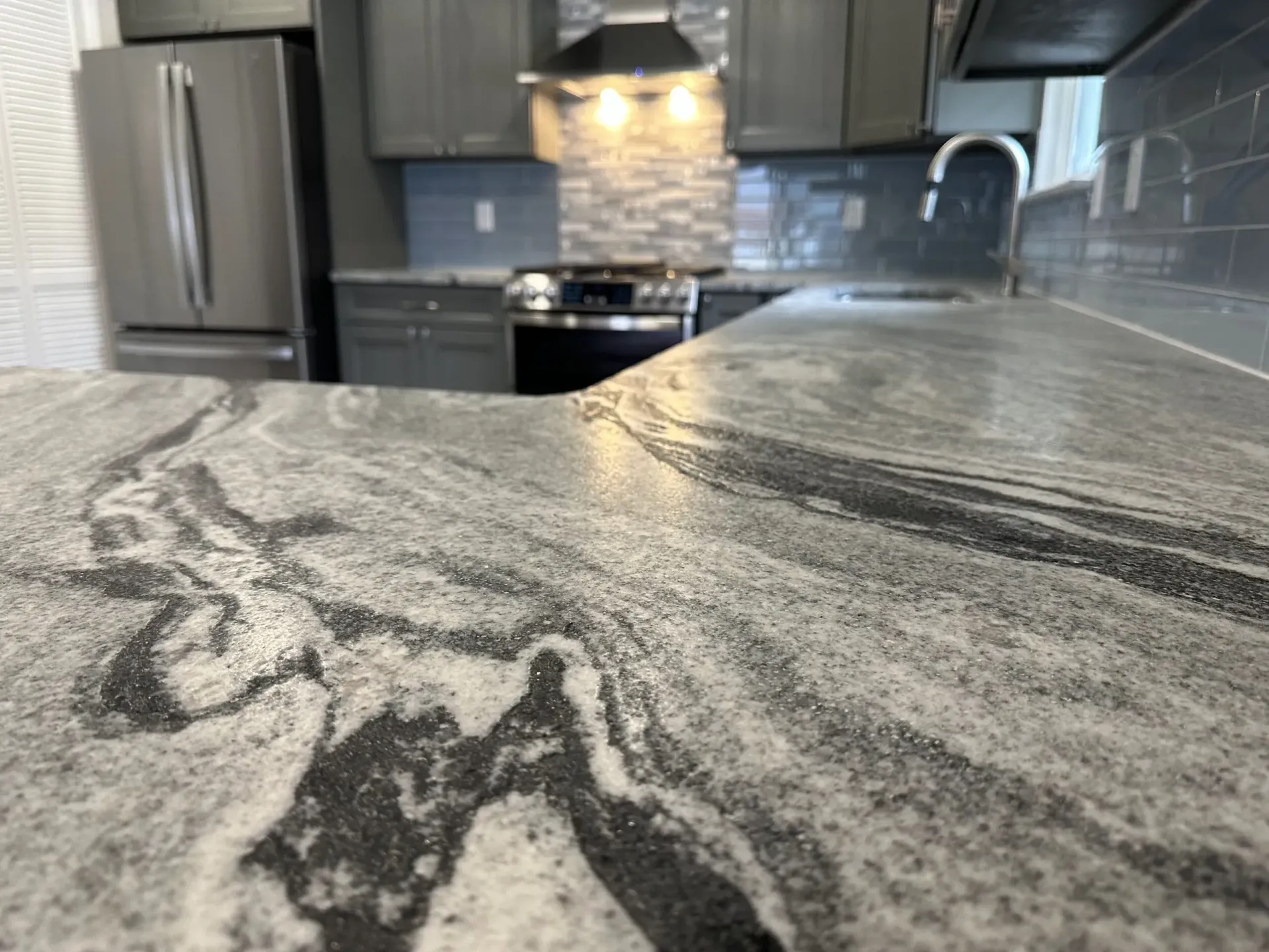 A kitchen with a granite counter top and stainless steel appliances.