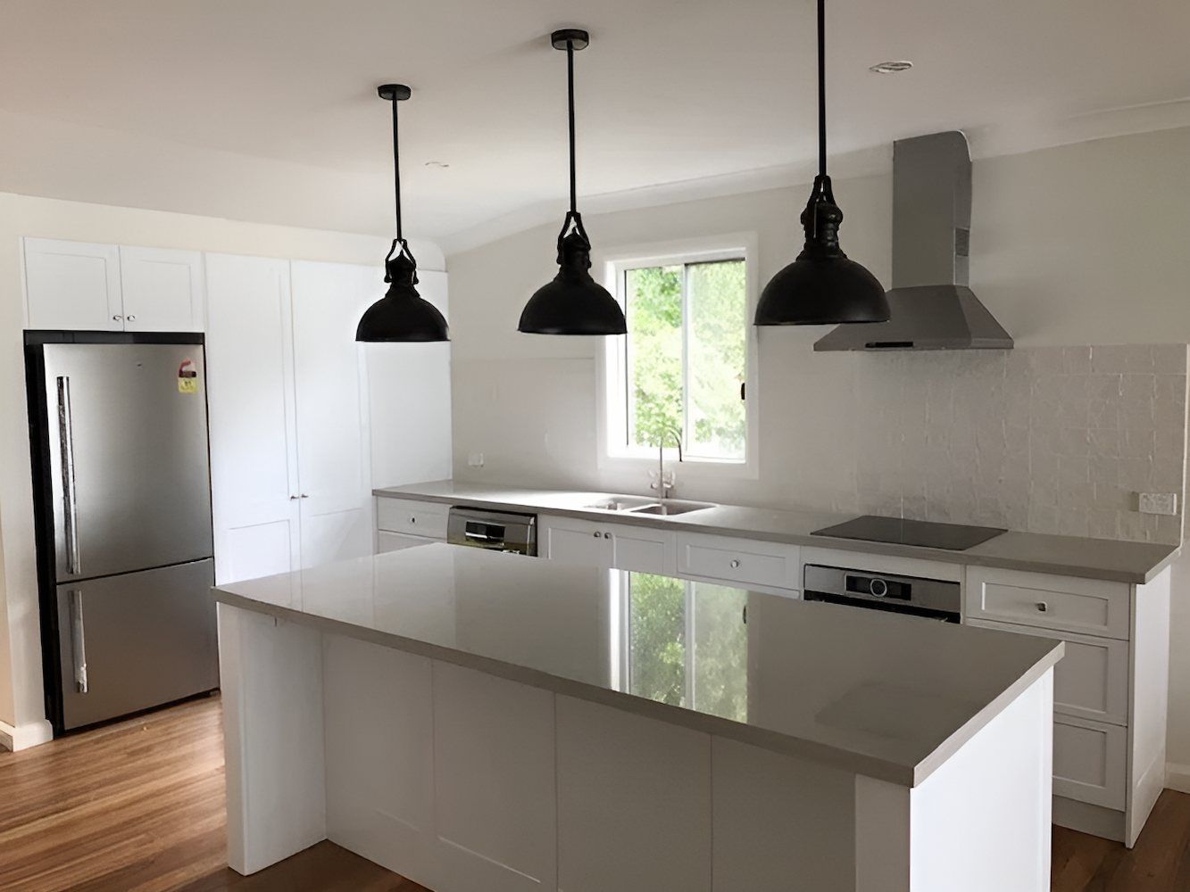 A Kitchen With White Cabinets, Stainless Steel Appliances, and a Large Island — East Maitland Building In Branxton, NSW