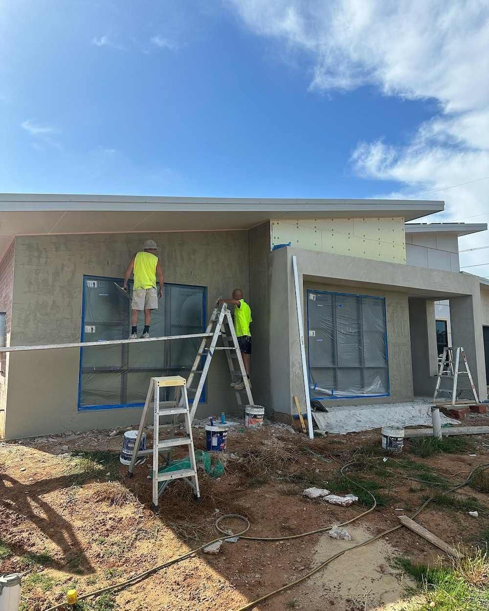 A Man is Standing on a Ladder Painting a House — East Maitland Building In Branxton, NSW