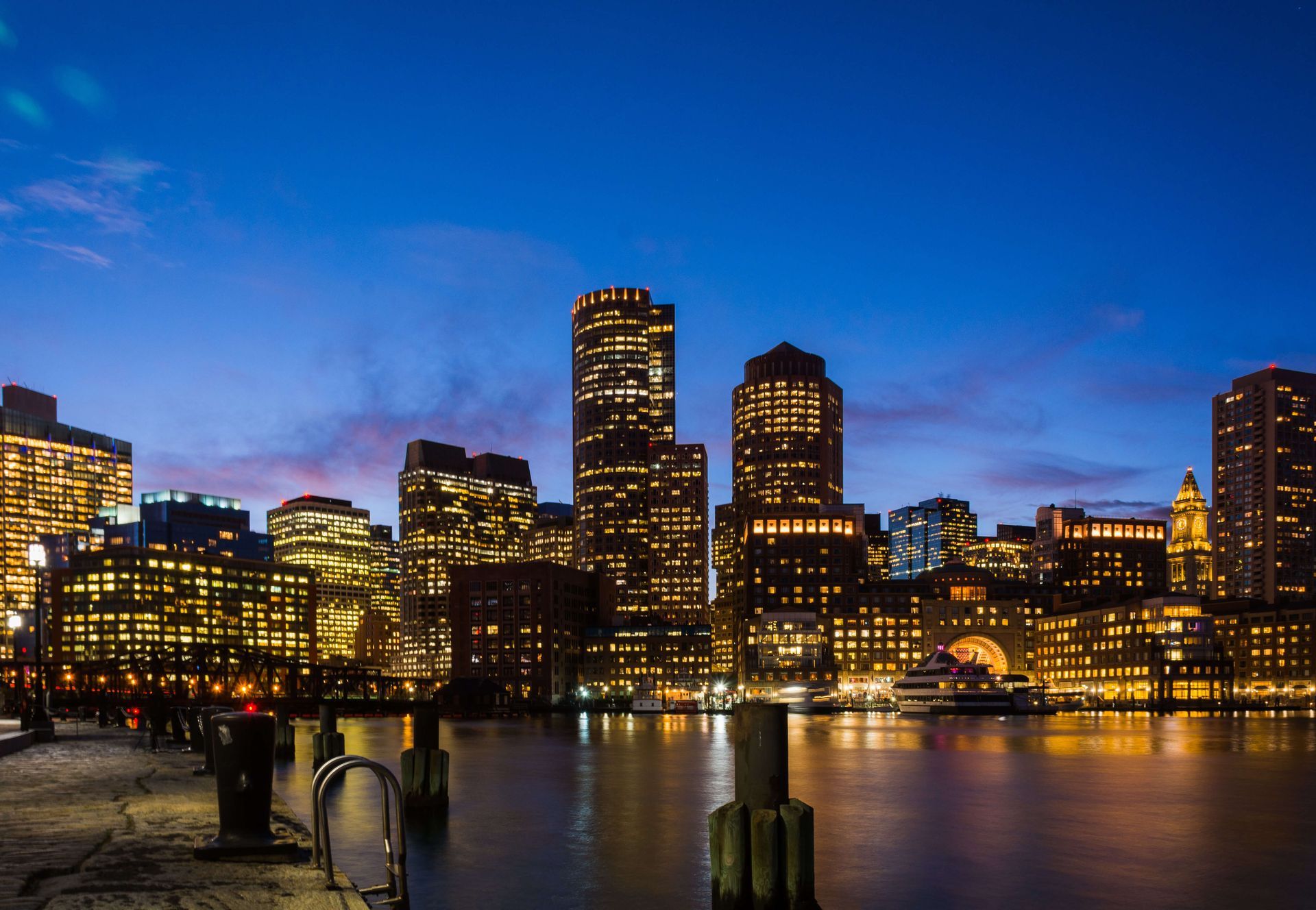 A city skyline at night with a body of water in the foreground.