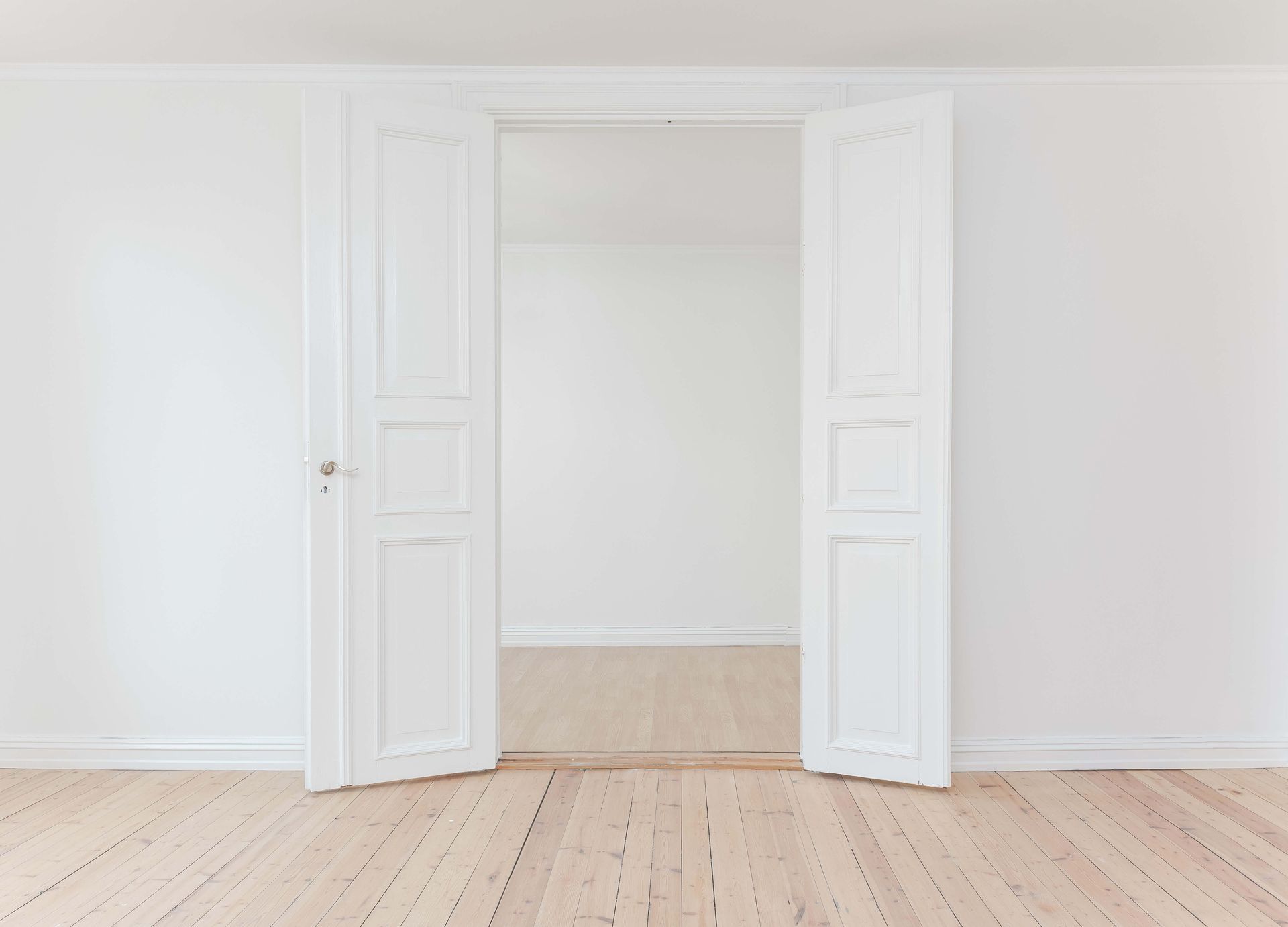An empty room with white walls and a wooden floor.